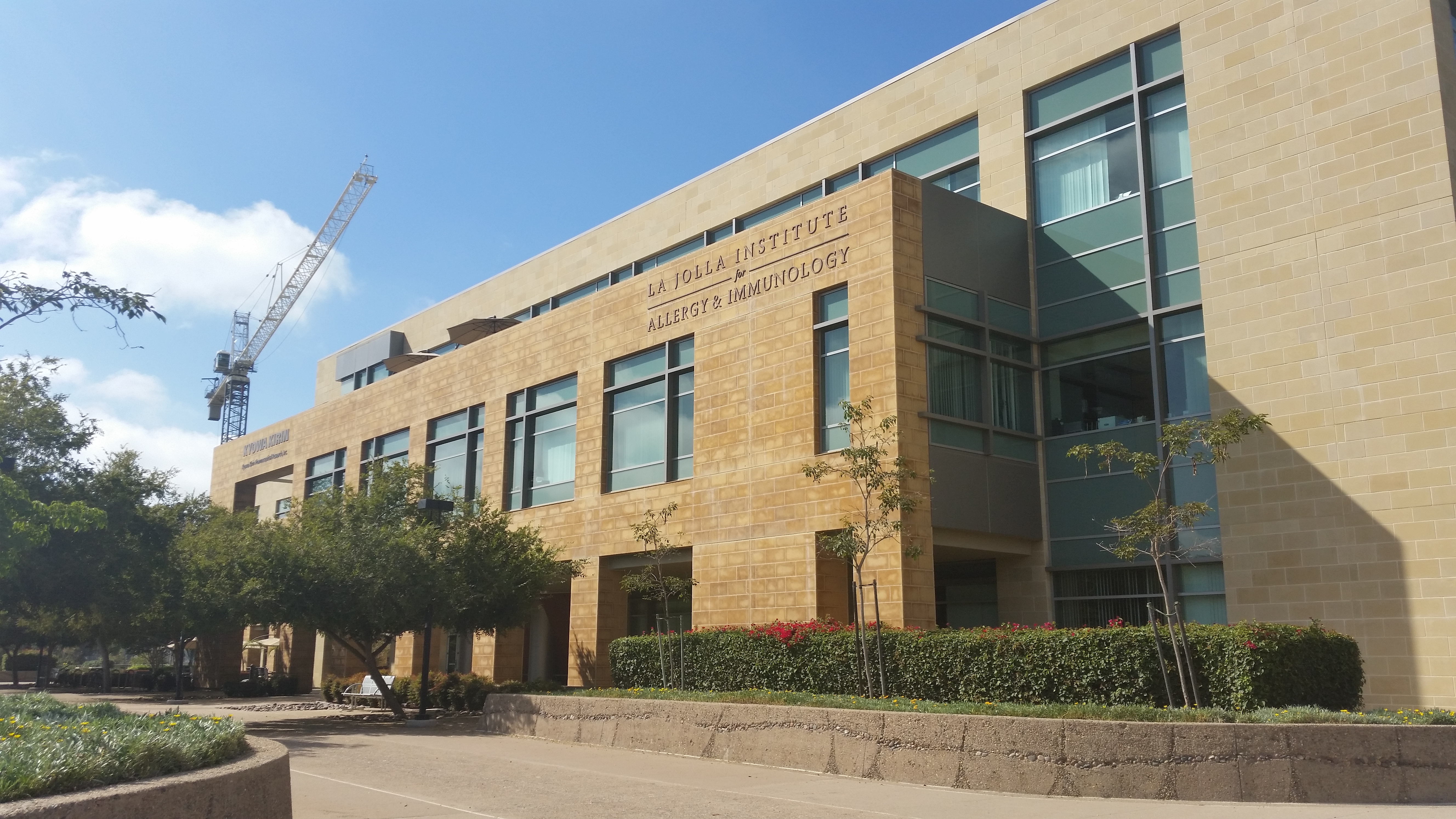 Exterior of a multi-story tan stone research building with large glass windows.