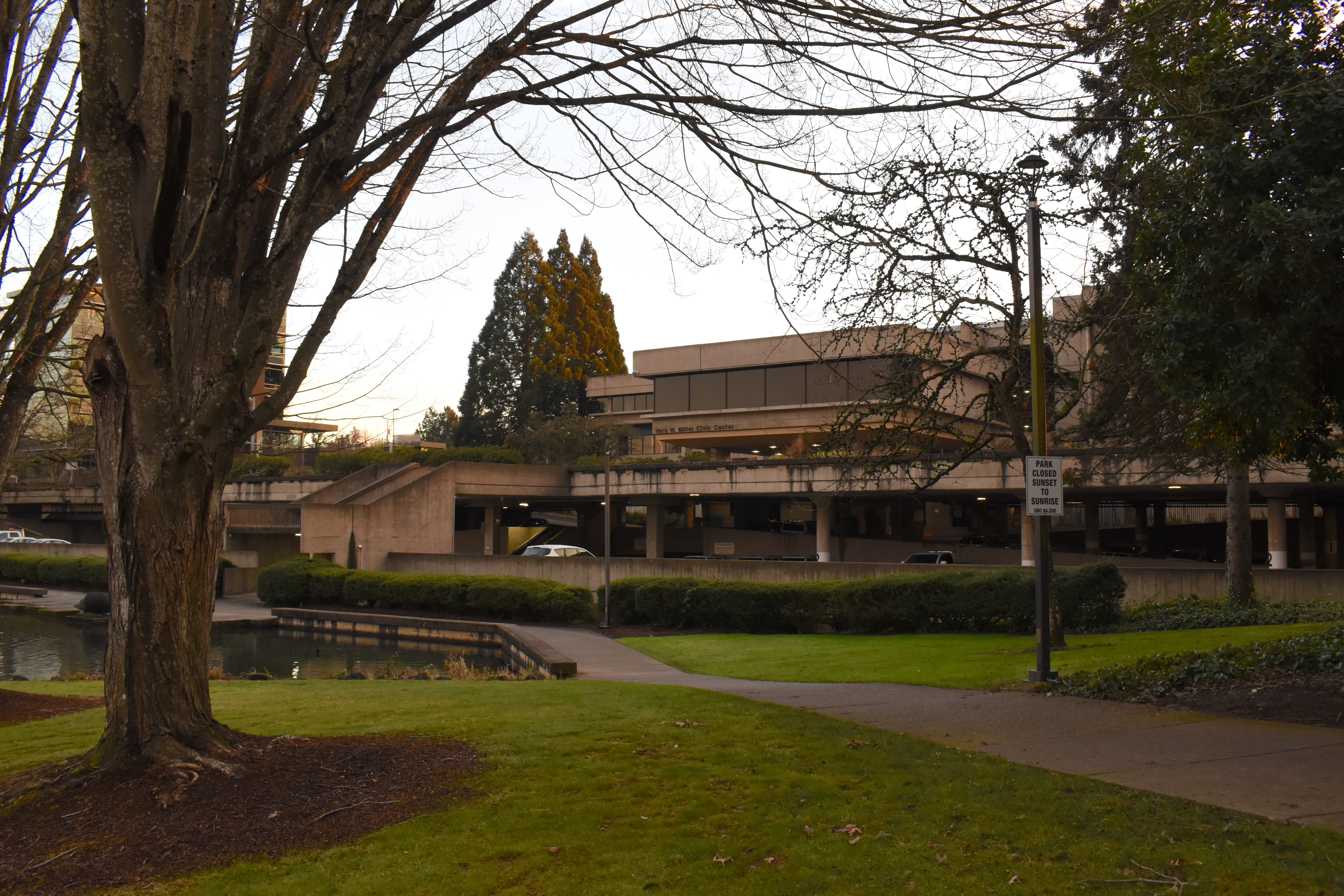 Pathway and mirror pond in front of a brutalist concrete civic center building.