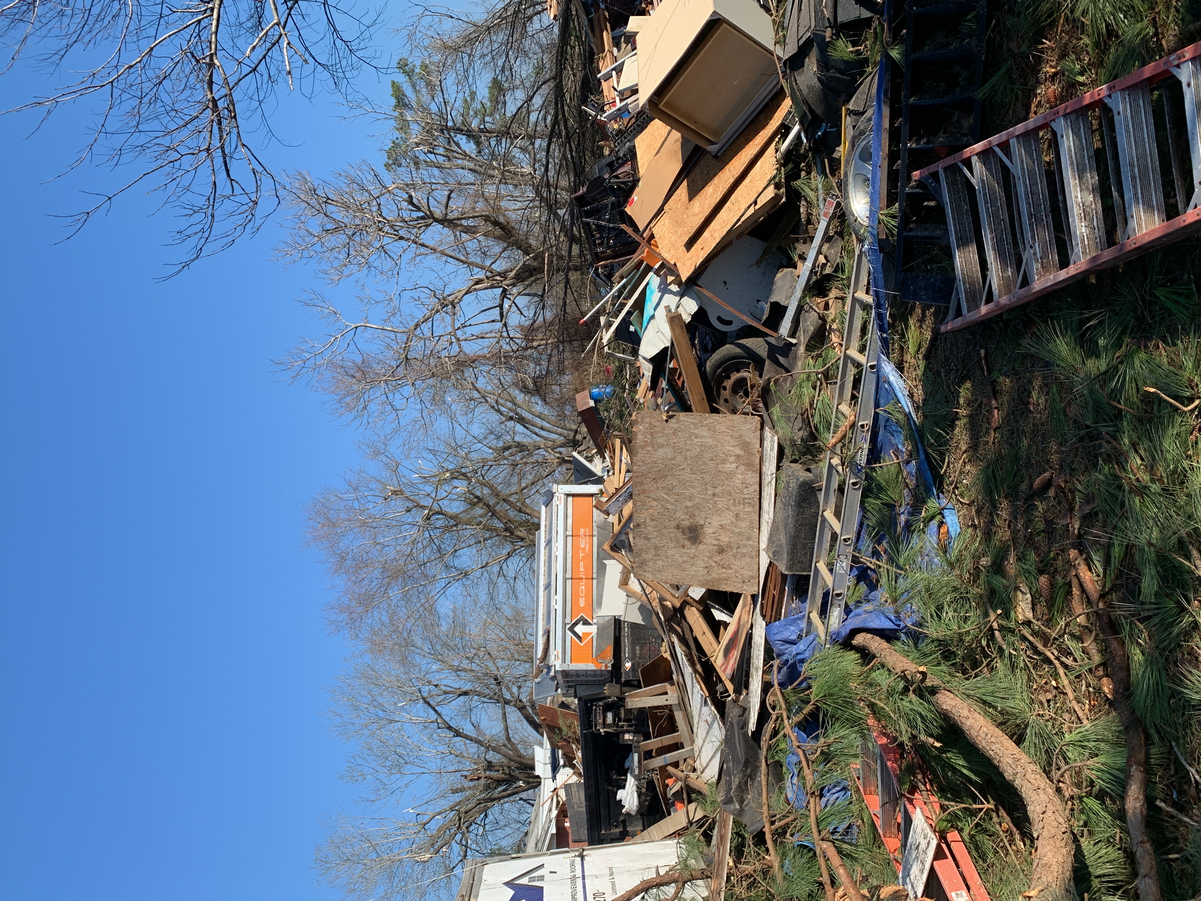 Debris pile of broken lumber and building materials from a tornado-destroyed structure.