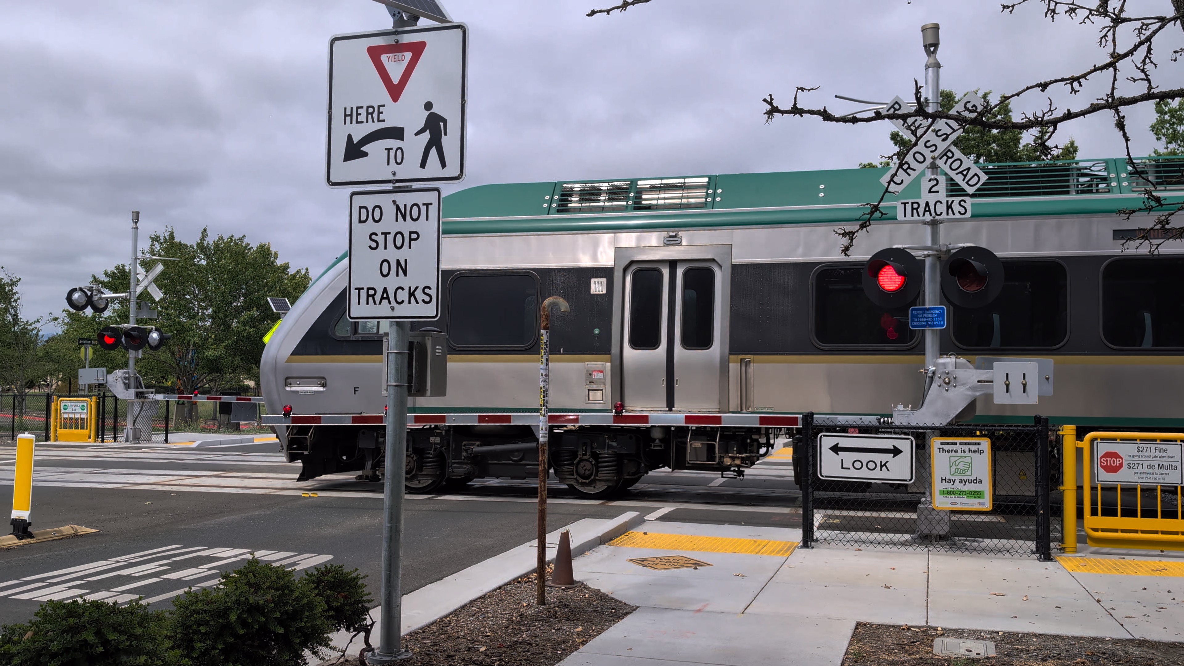 A SMART train moves through a grade crossing with gates and warning signs.