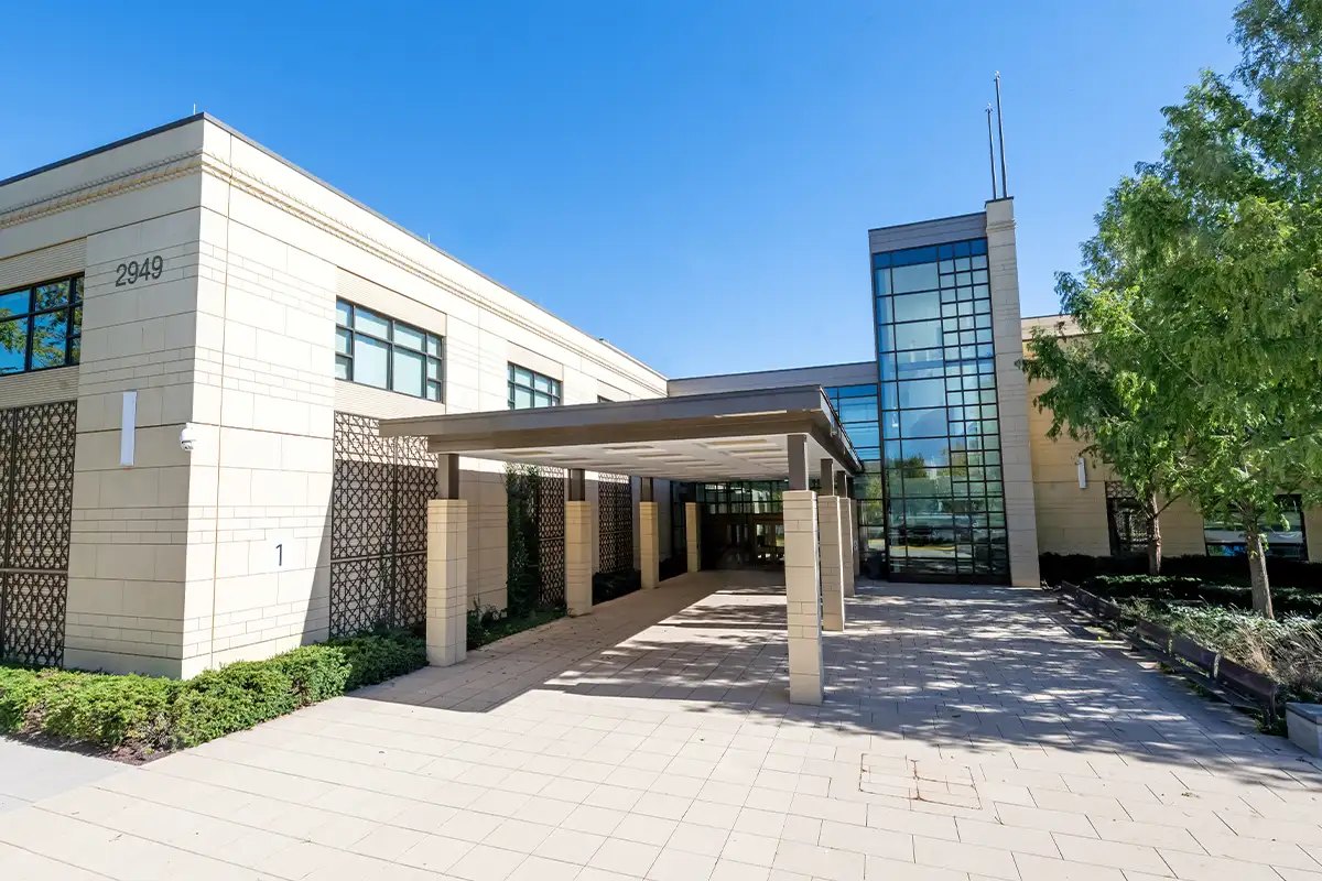 Exterior of a modern two-story school building with a covered entrance and glass tower.