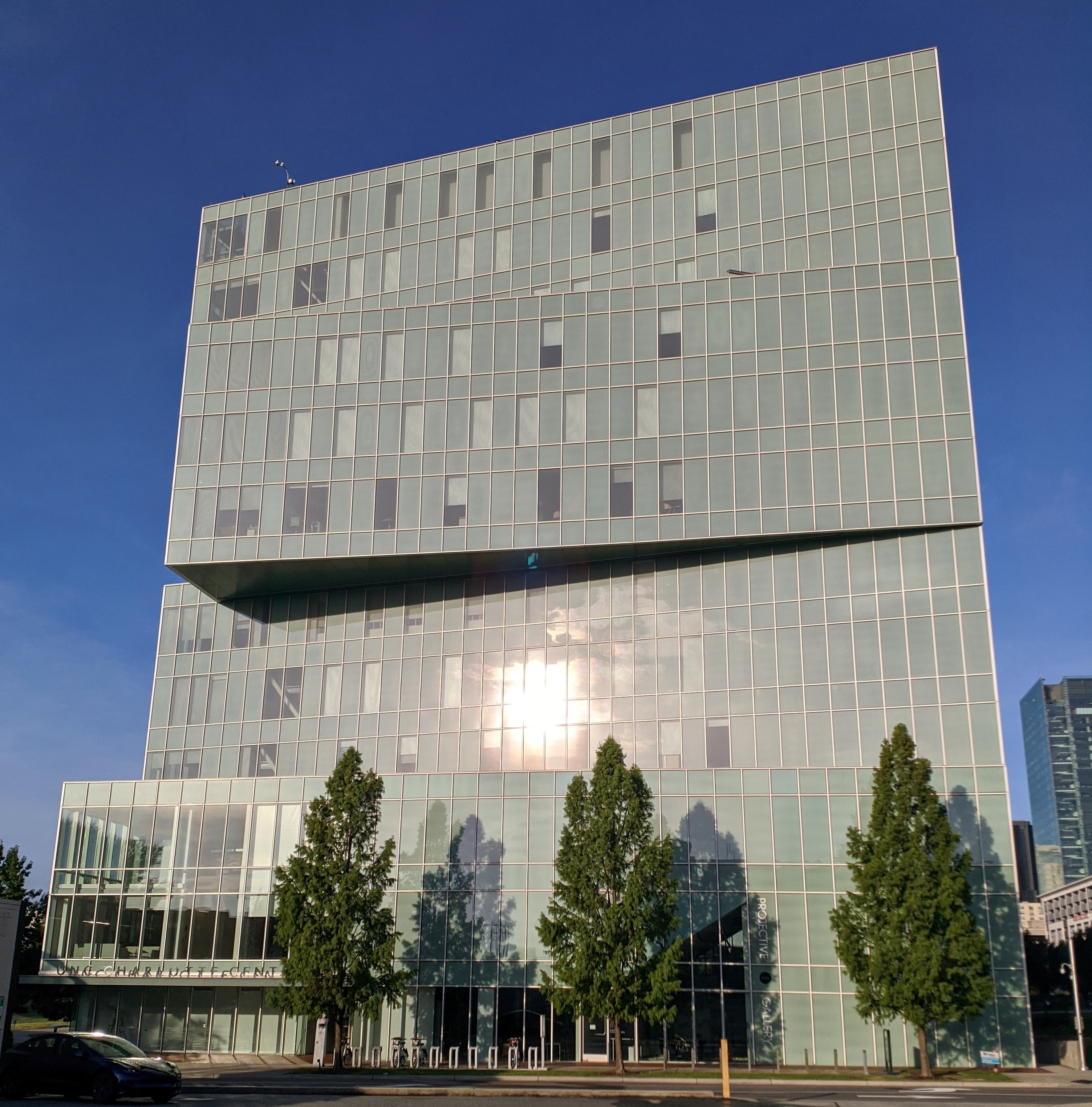 Modern glass-and-steel university building with trees lining the entrance.