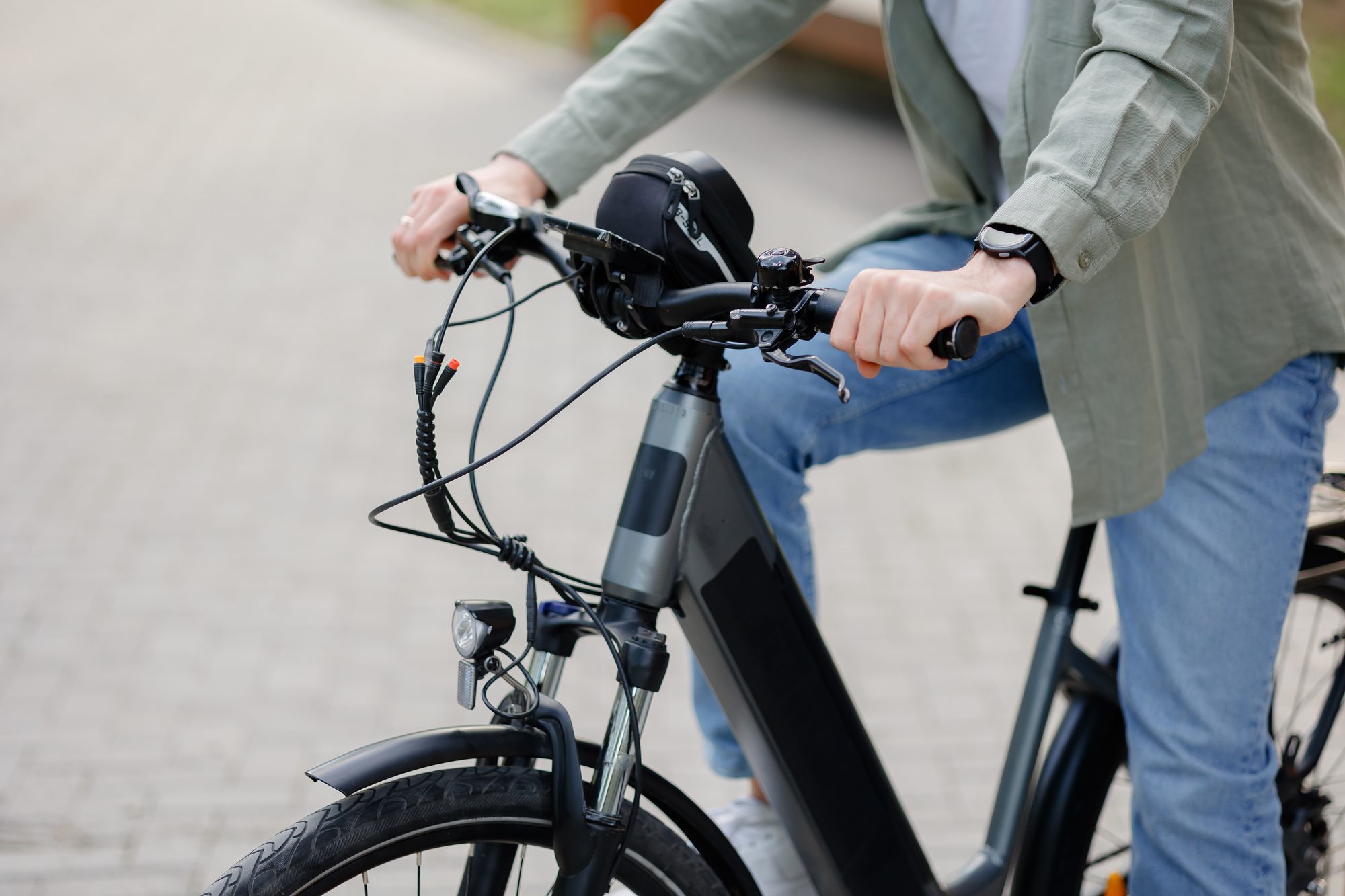 Person riding an electric bike on a brick pathway during daytime in a park setting