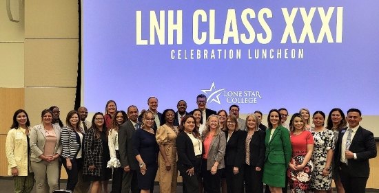 Large group of professionals posing in front of a screen reading LNH Class XXXI Celebration Luncheon.