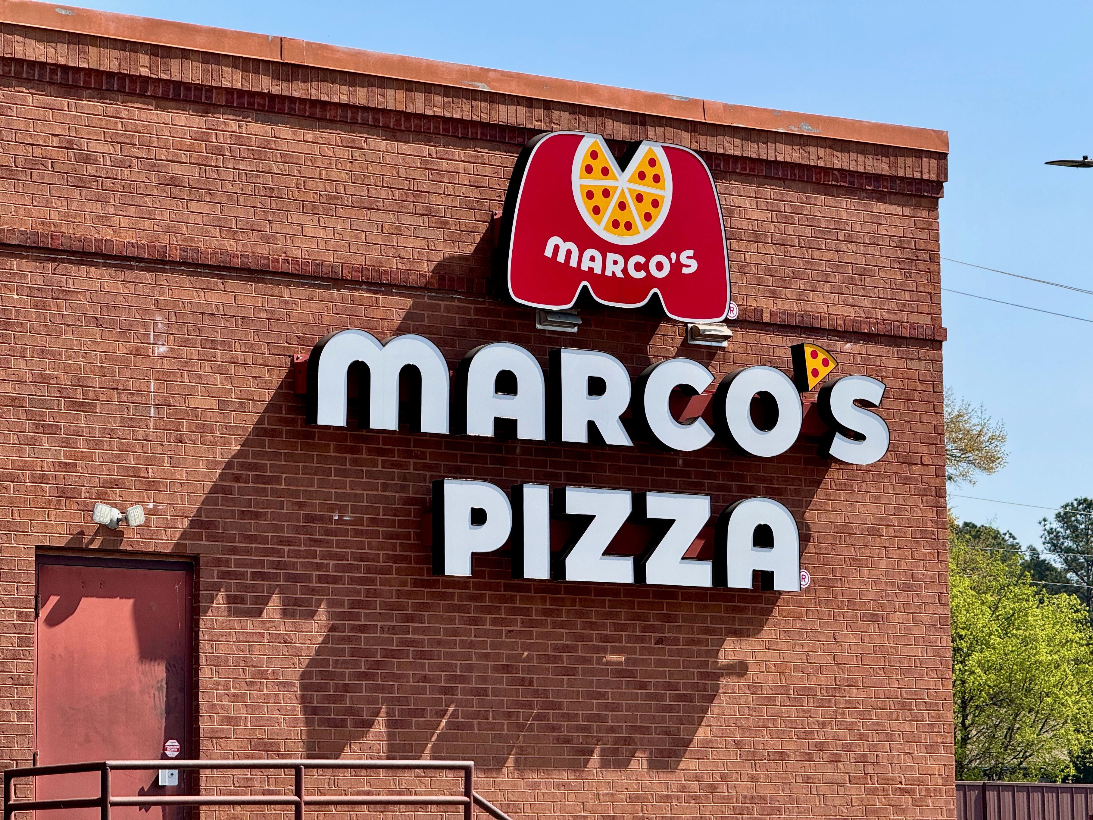 Brick exterior of a Marco's Pizza restaurant with large brand sign.