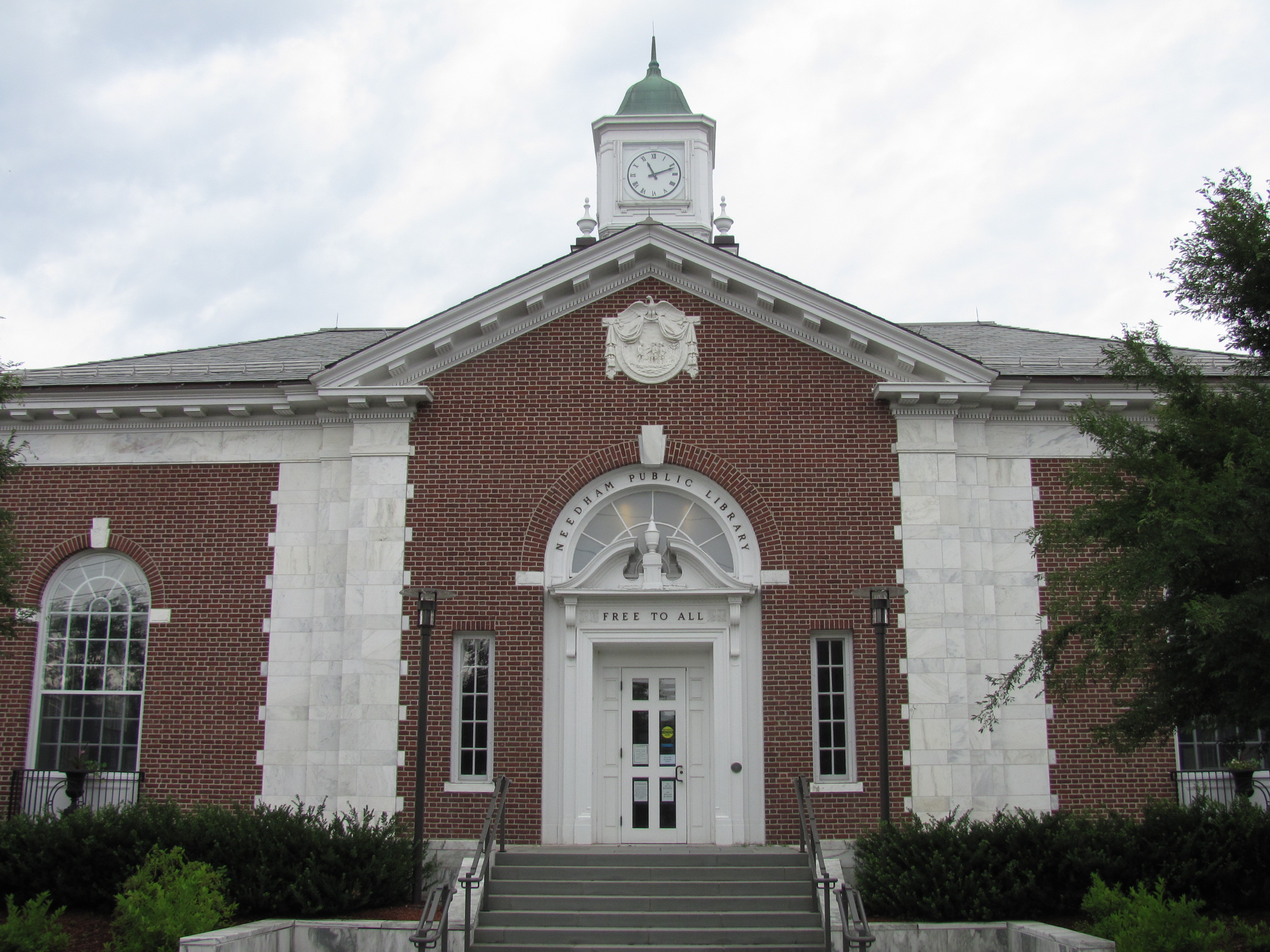 Red brick public library building with clock tower and 'FREE TO ALL' inscription above the entrance.