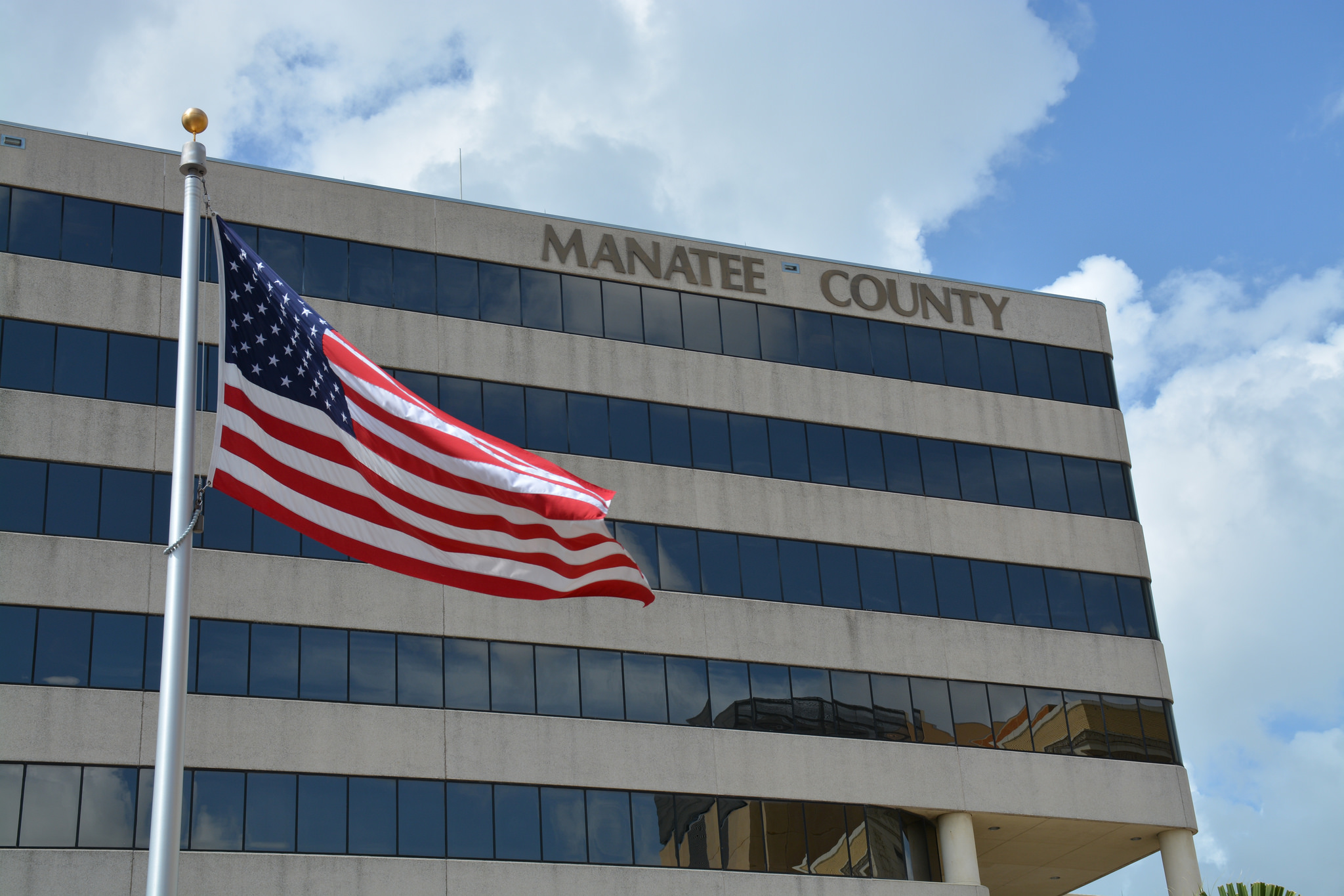 Exterior of the Manatee County Administration Building with an American flag in the foreground.