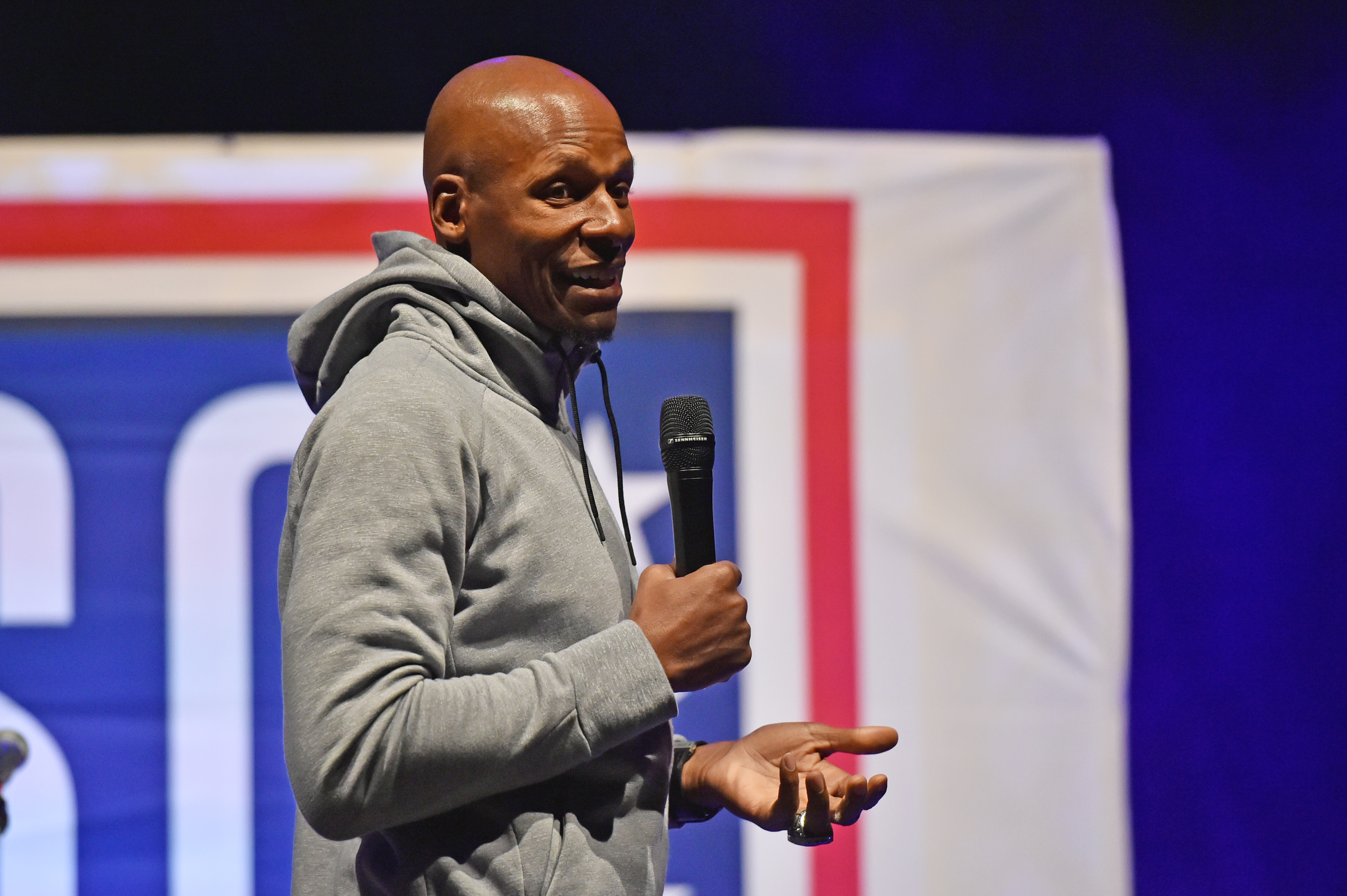 Ray Allen in a gray hoodie speaking into a microphone on stage.