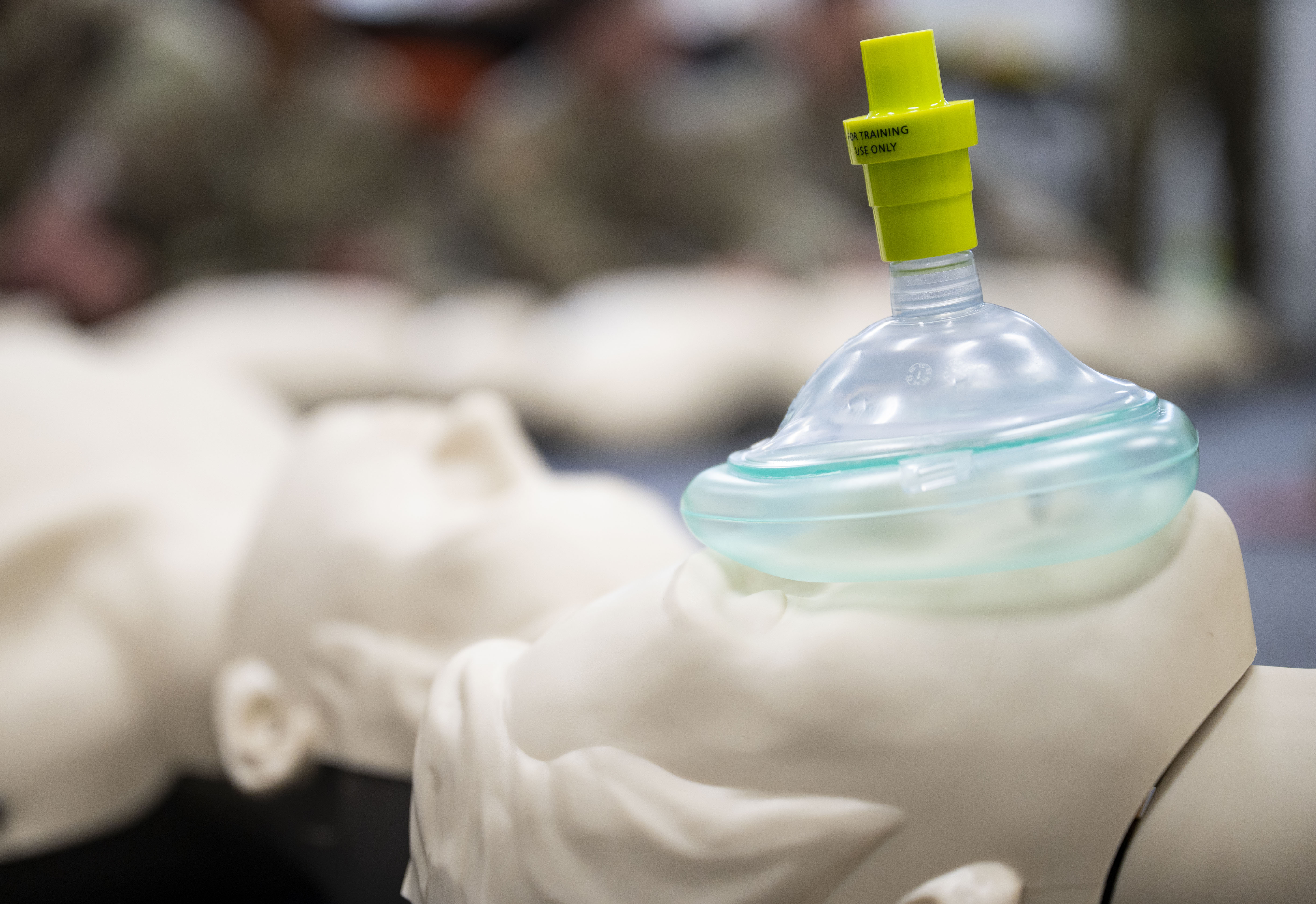 A clear CPR pocket mask with a yellow valve resting on a white training mannequin.