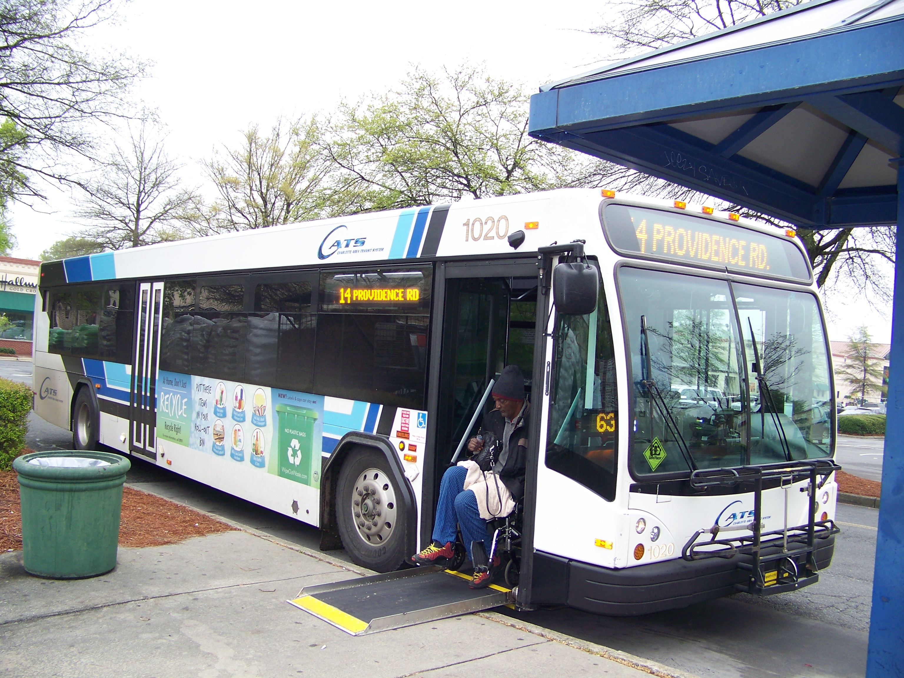 A CATS transit bus stopped at a covered blue-roofed shelter with a boarding ramp deployed.