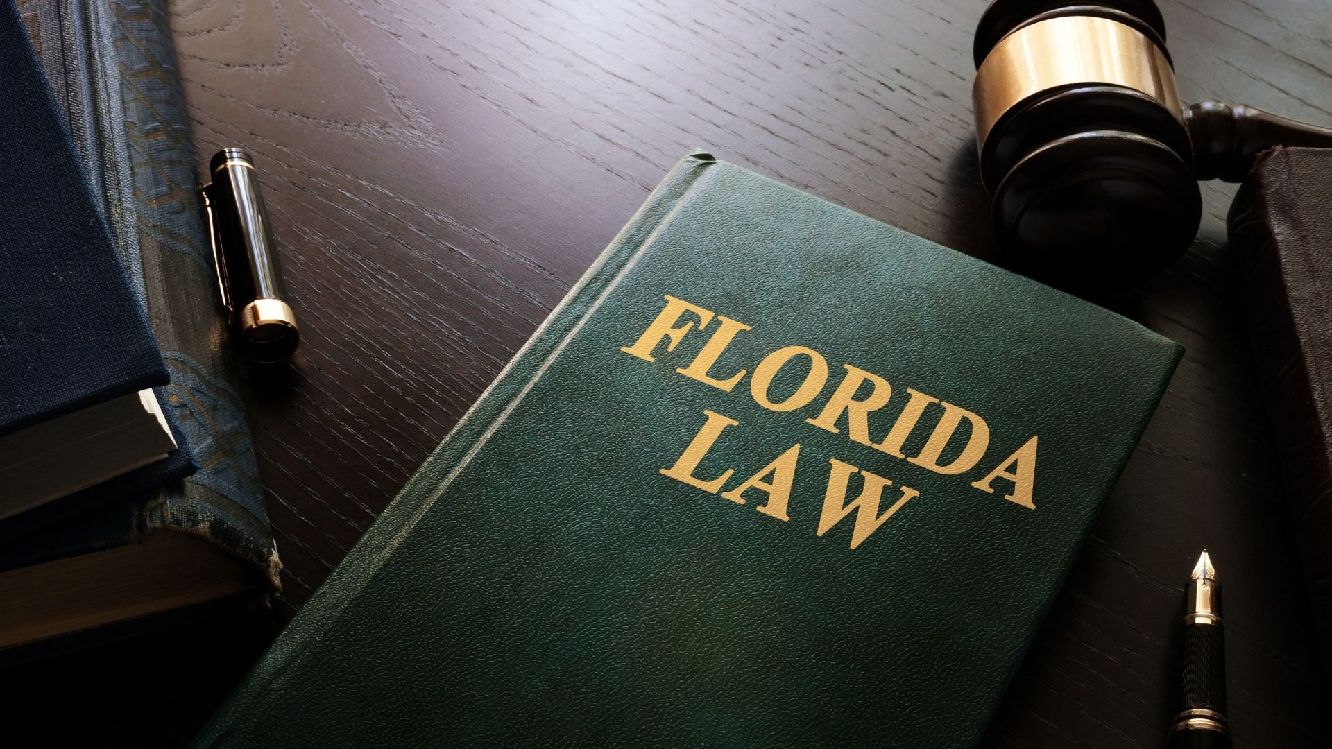A green book labeled Florida Law on a desk beside a wooden gavel and pens.