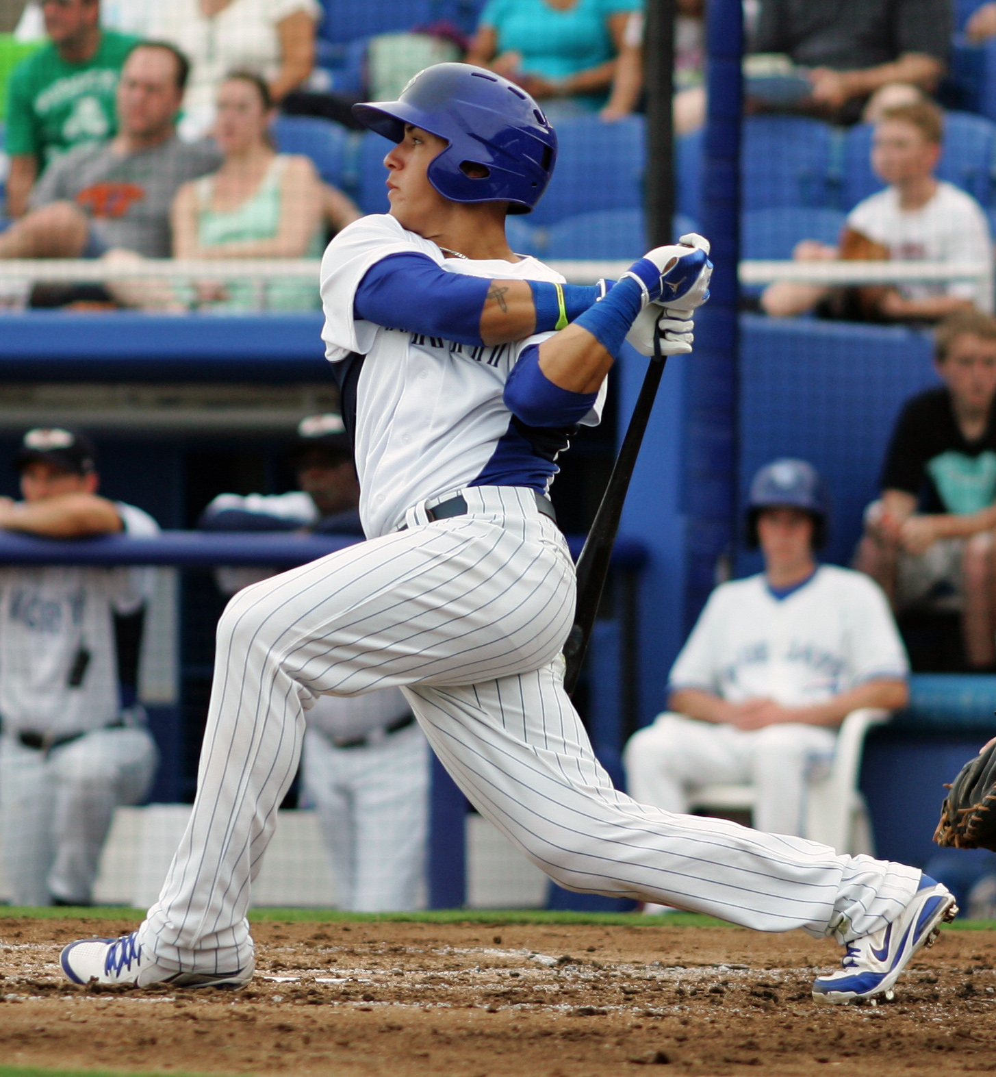 A baseball batter in a blue Dunedin Blue Jays uniform follows through on a swing.