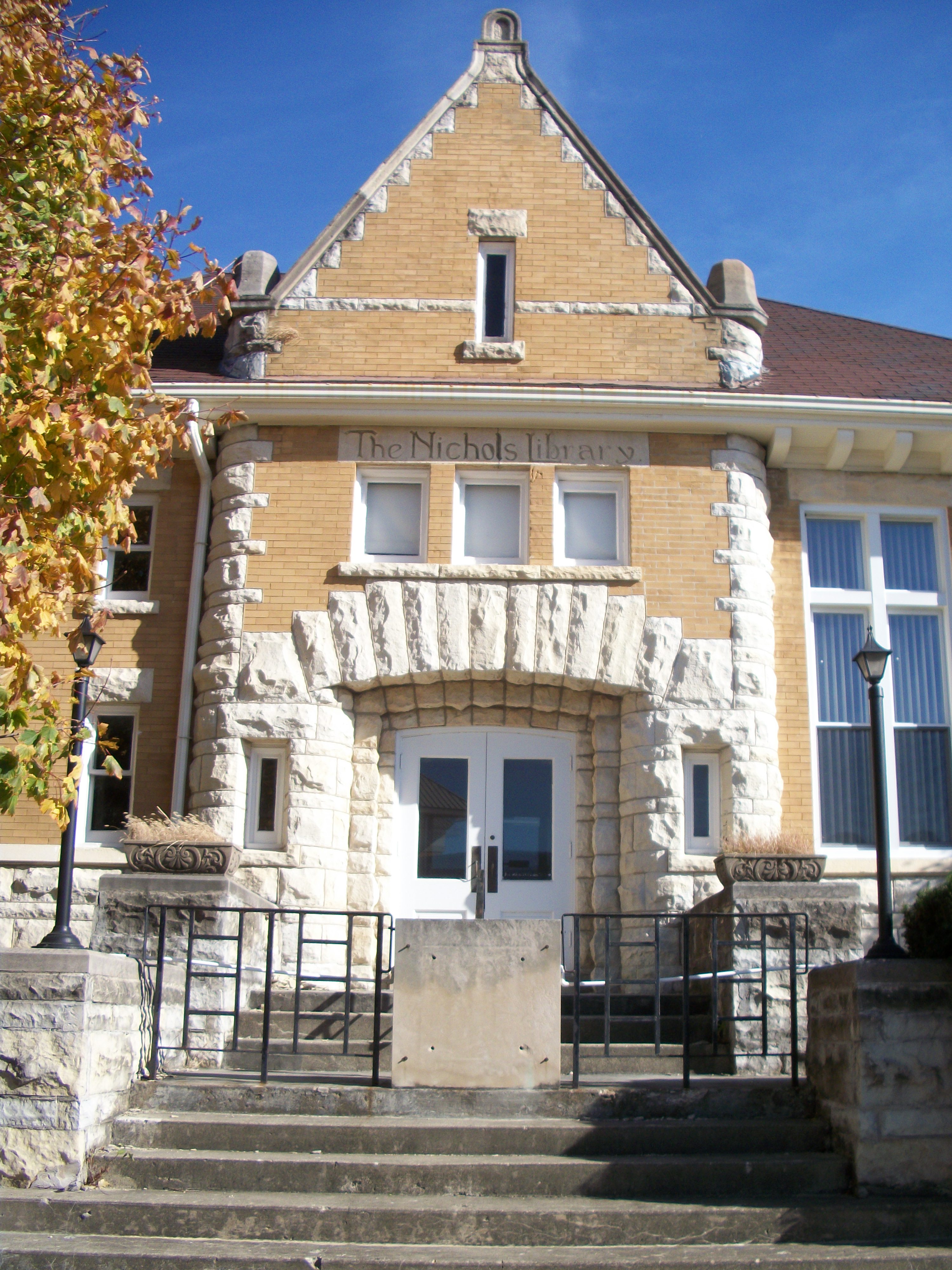 Brick library building with arched stone entrance and autumn foliage.