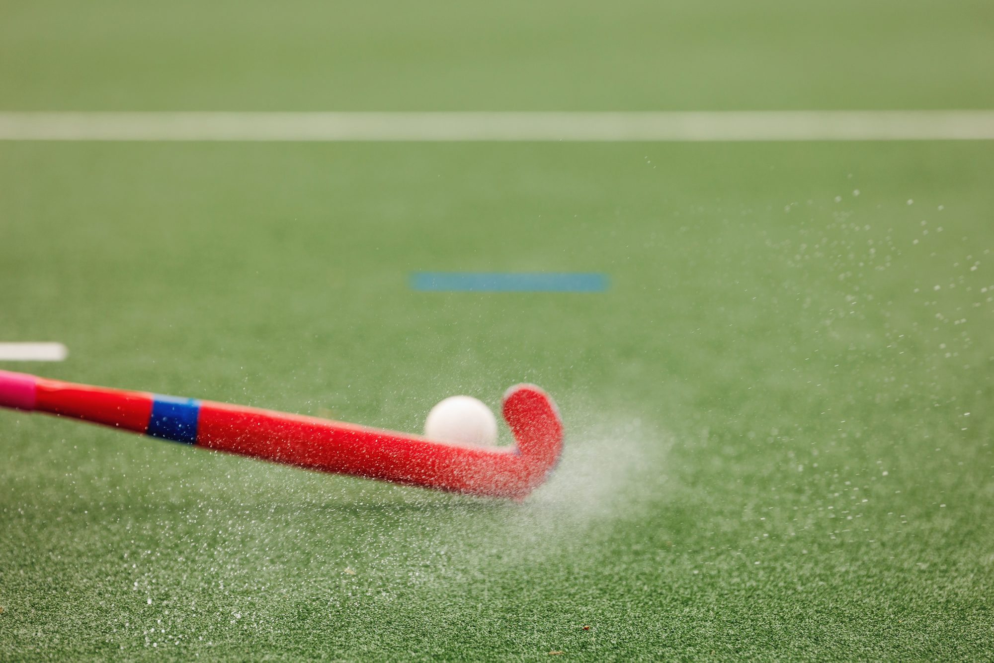 Field hockey ball being struck by field hockey stick at high speed