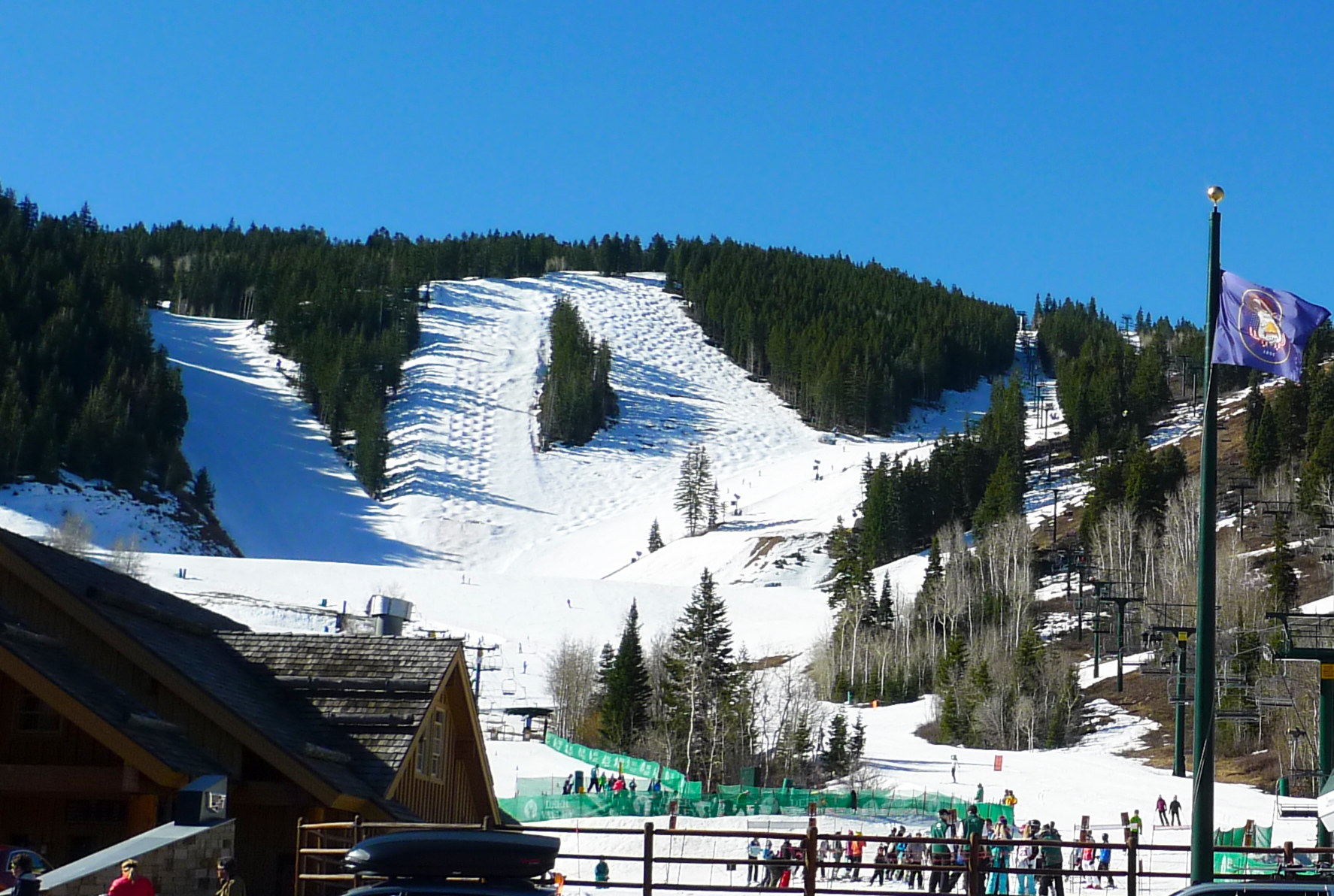 Snow-covered mogul ski runs and a chairlift on a forested mountain slope.