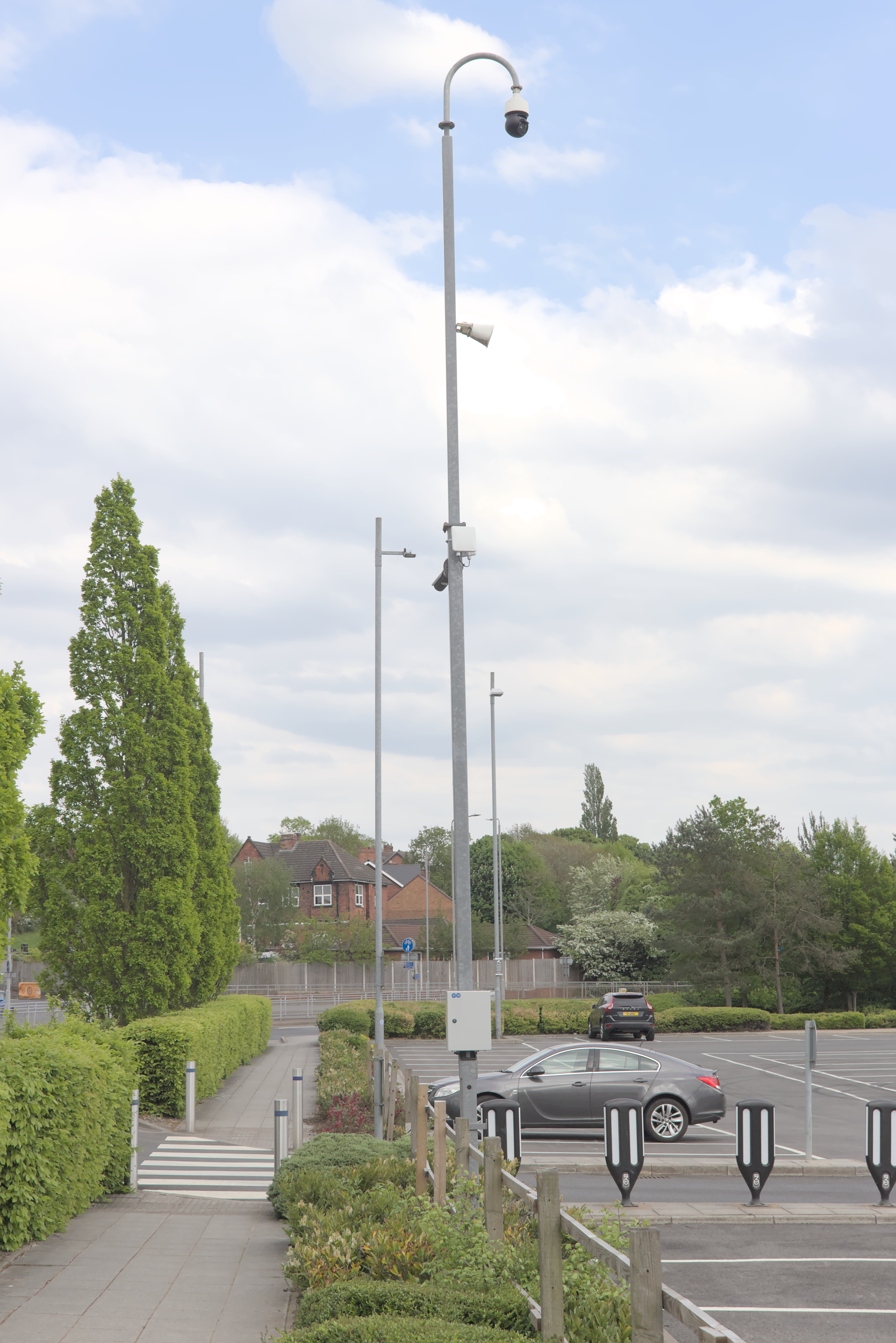 Dome surveillance camera mounted on a tall metal pole outdoors.