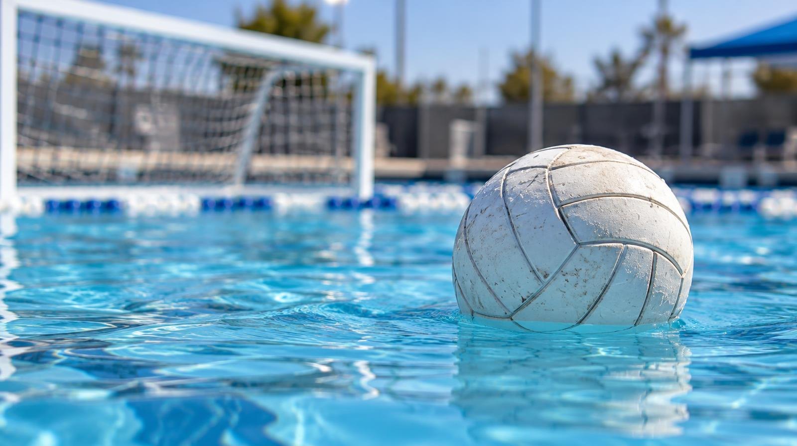 White water polo ball floating on the surface of a bright blue outdoor pool.