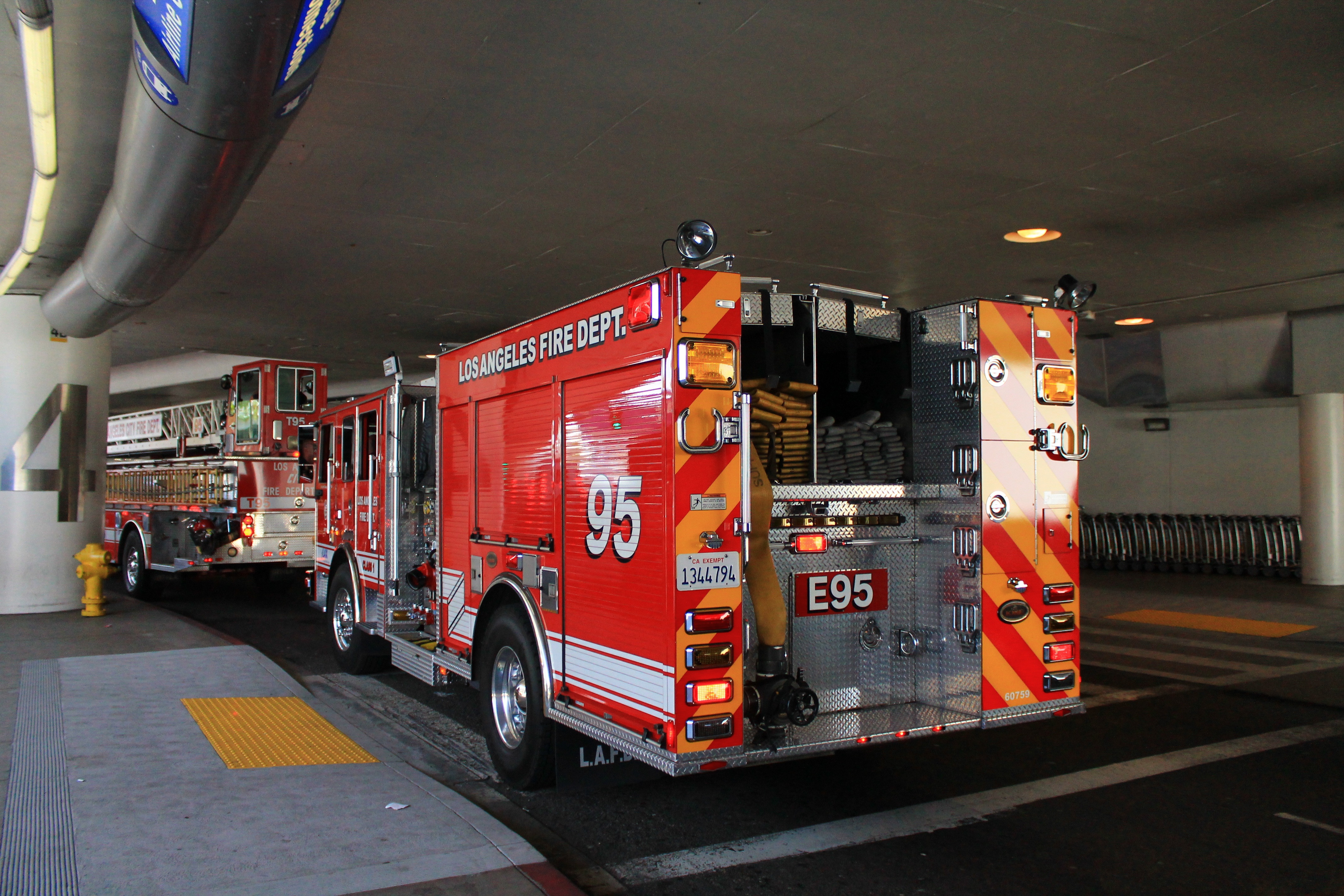 Two red Los Angeles Fire Department fire engines parked under a covered overhang.