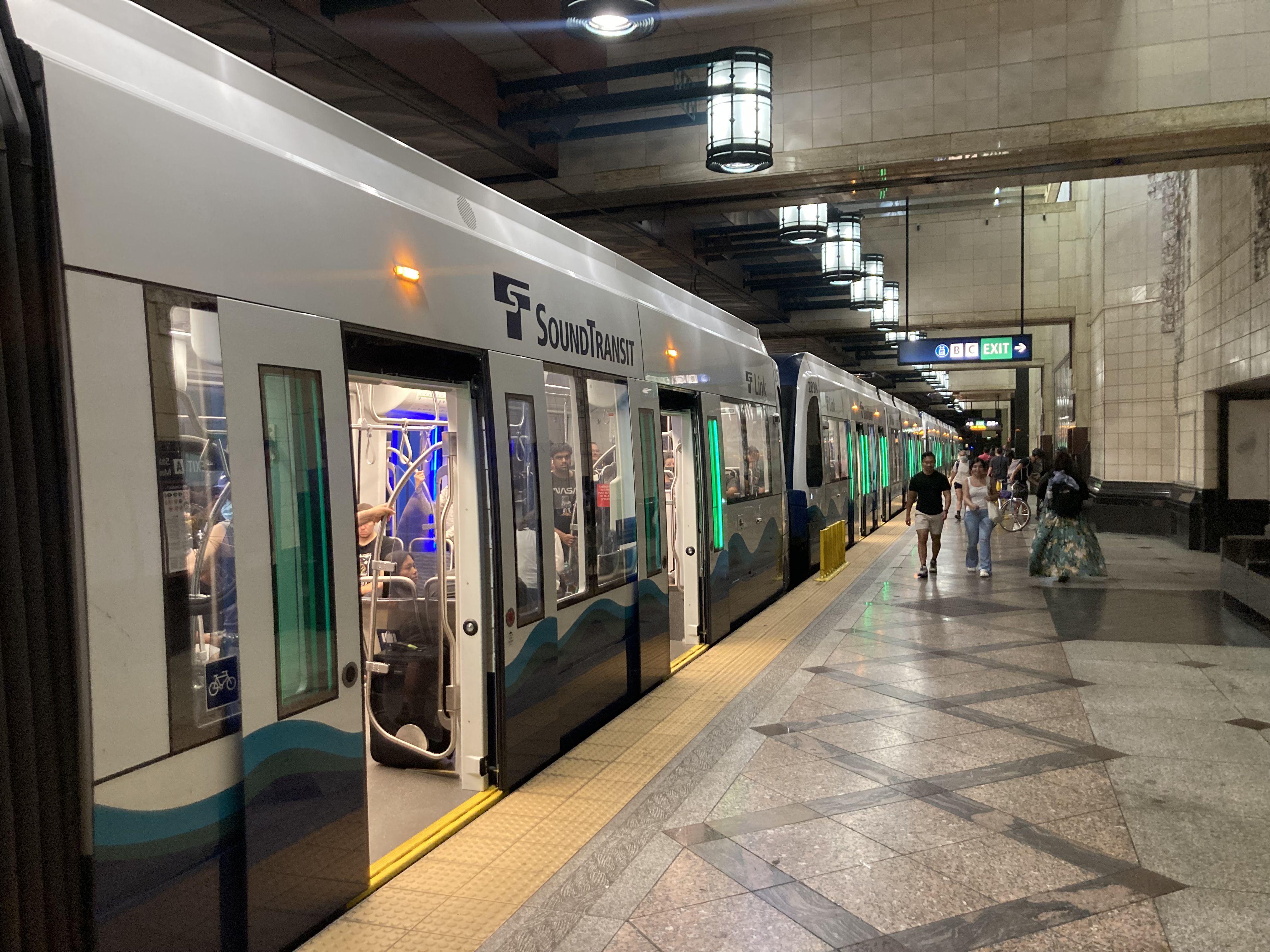 Passengers boarding a Link Light Rail train at an underground station platform.
