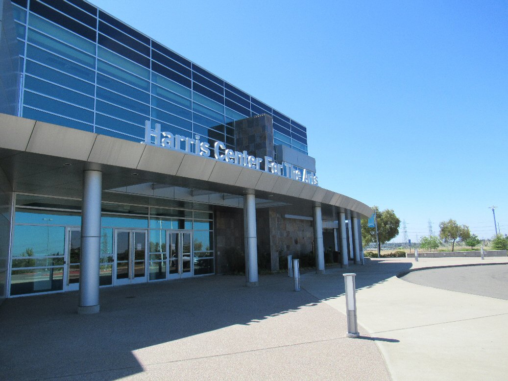 Exterior entrance of a performing arts building with glass facade and large venue signage.