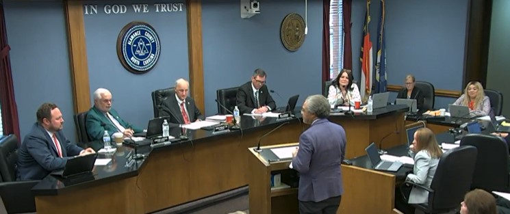 Officials seated at a raised dais in a county government meeting room.