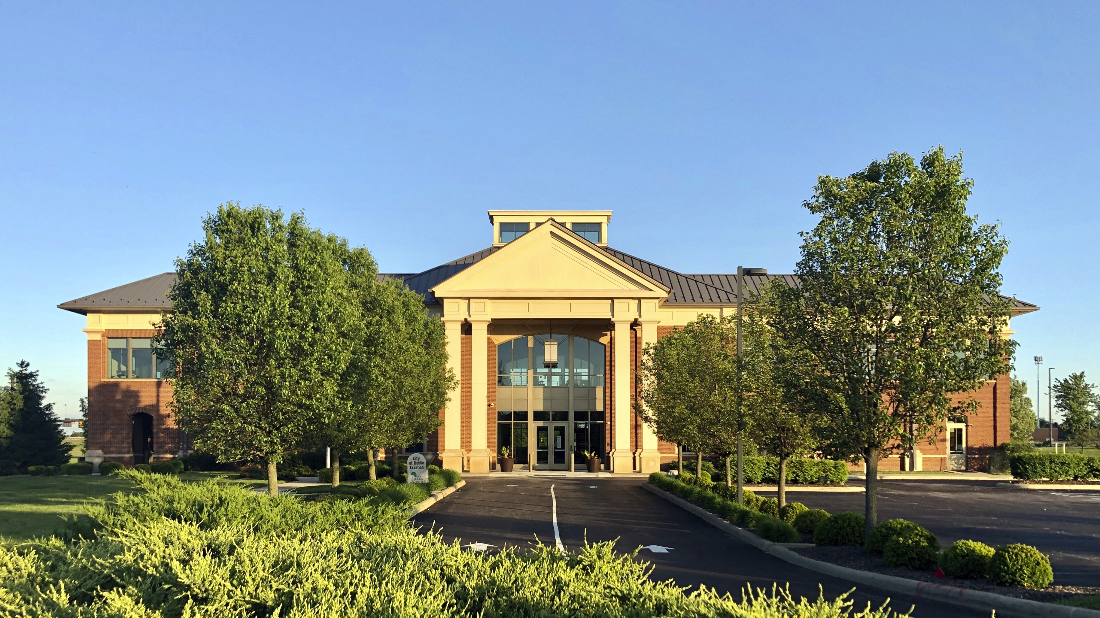 Two-story brick building with columned entrance portico and manicured landscaping.