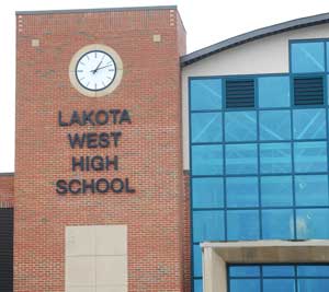 Brick exterior of a high school building with clock tower and glass gymnasium wing.