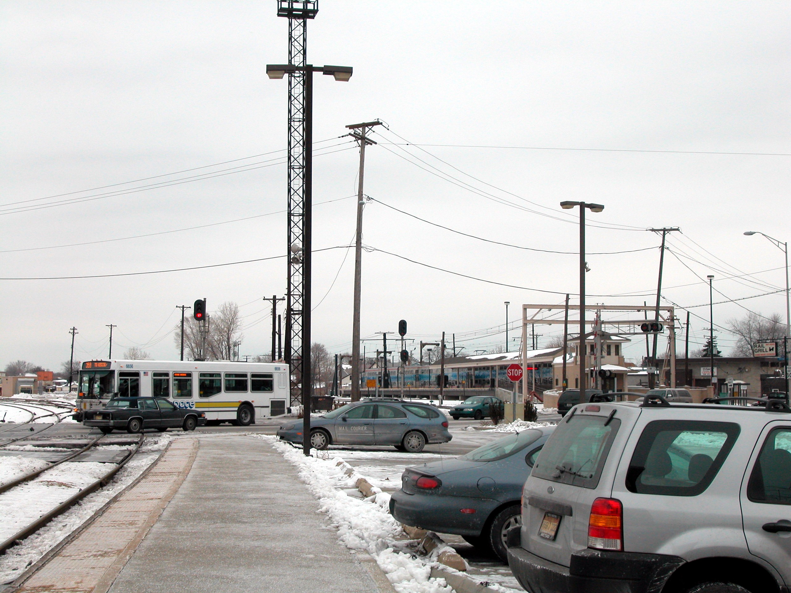 A Pace bus crosses a railroad grade crossing on a snowy suburban street.