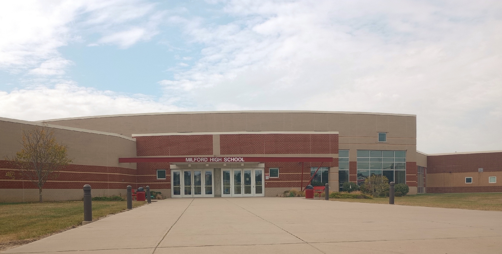 Exterior of a large brick high school building with glass entrance doors and a curved roofline.