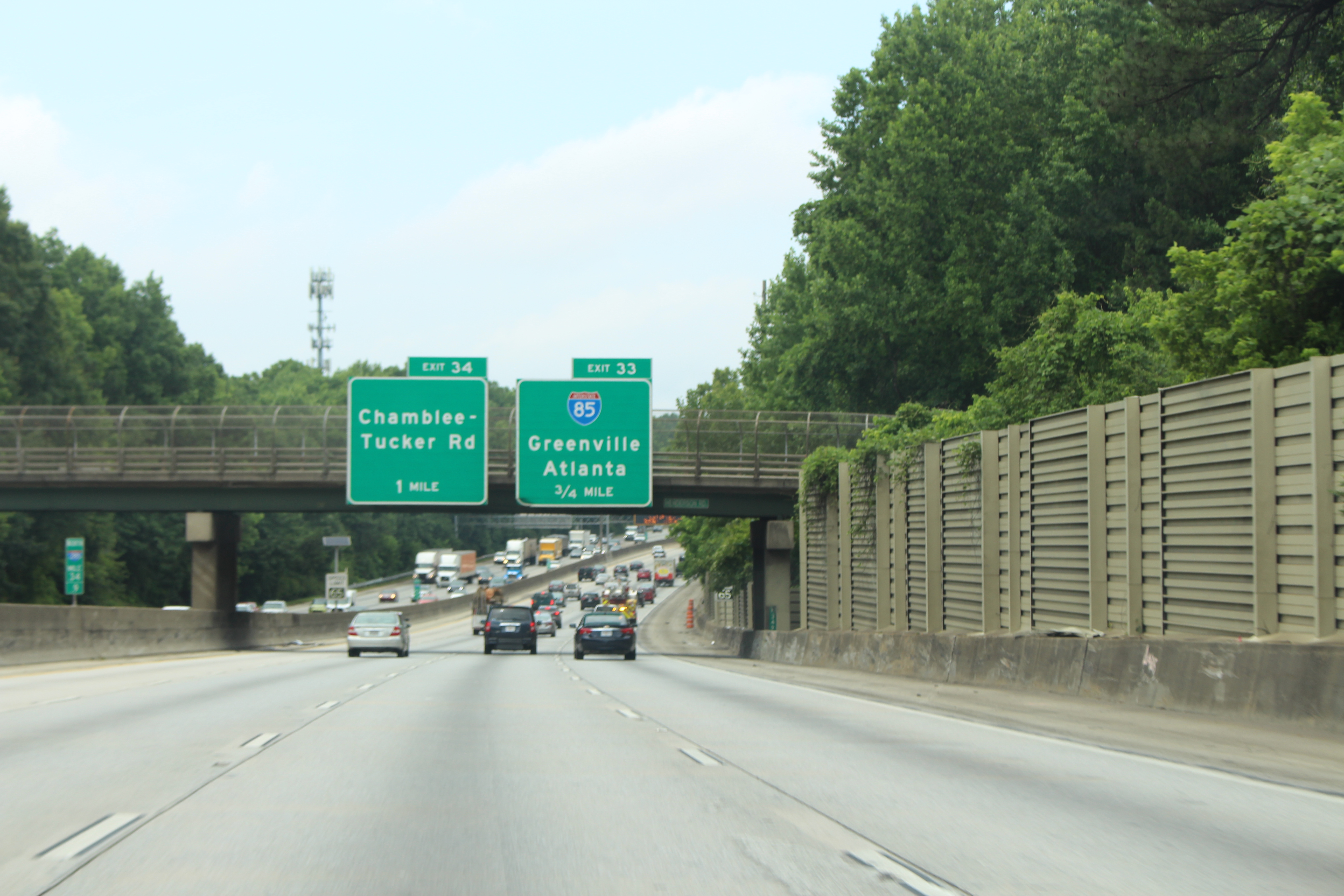 Northbound interstate highway with green overhead exit signs and a concrete overpass.