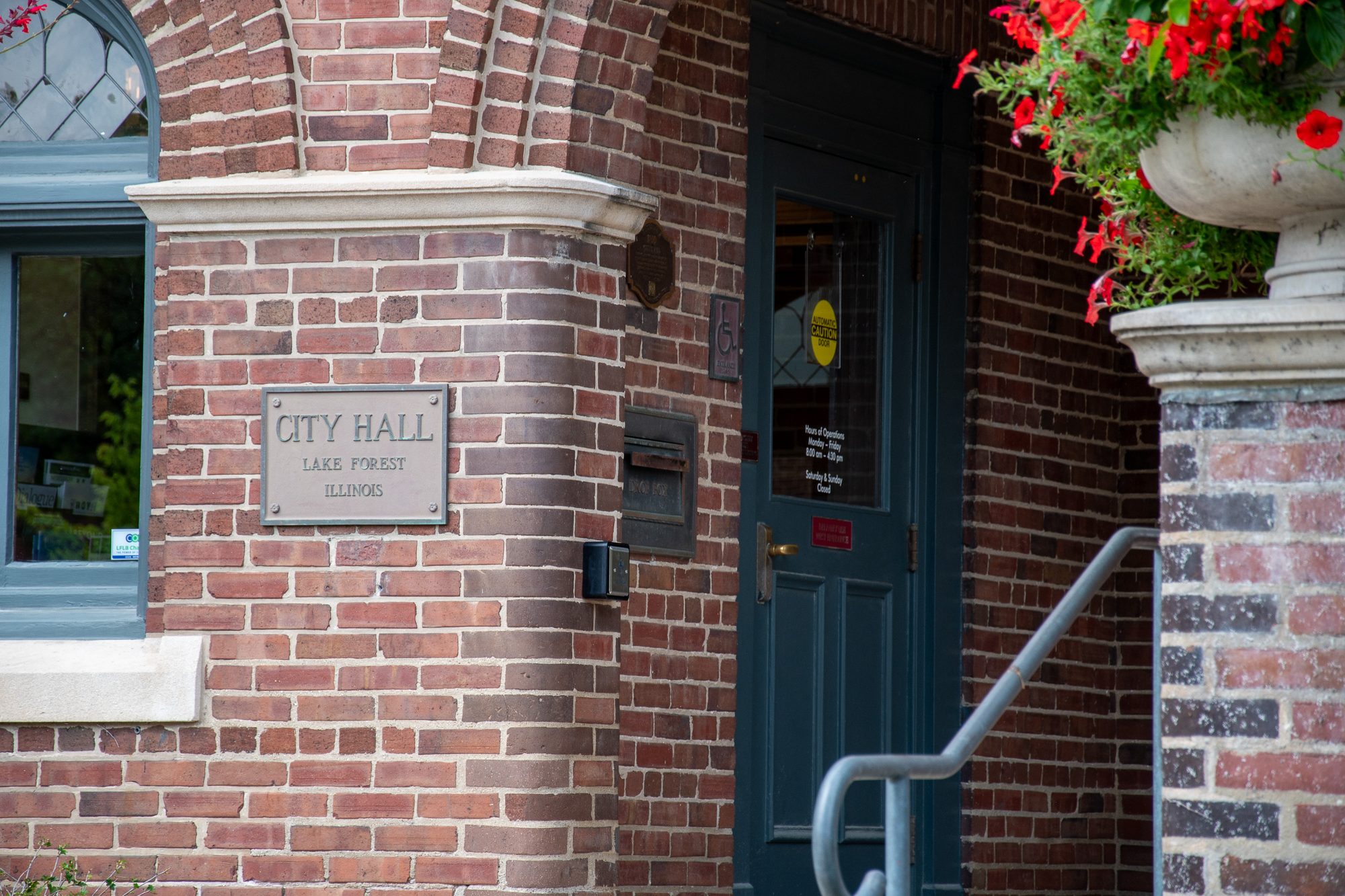 Brick building entrance with a City Hall plaque beside a teal door
