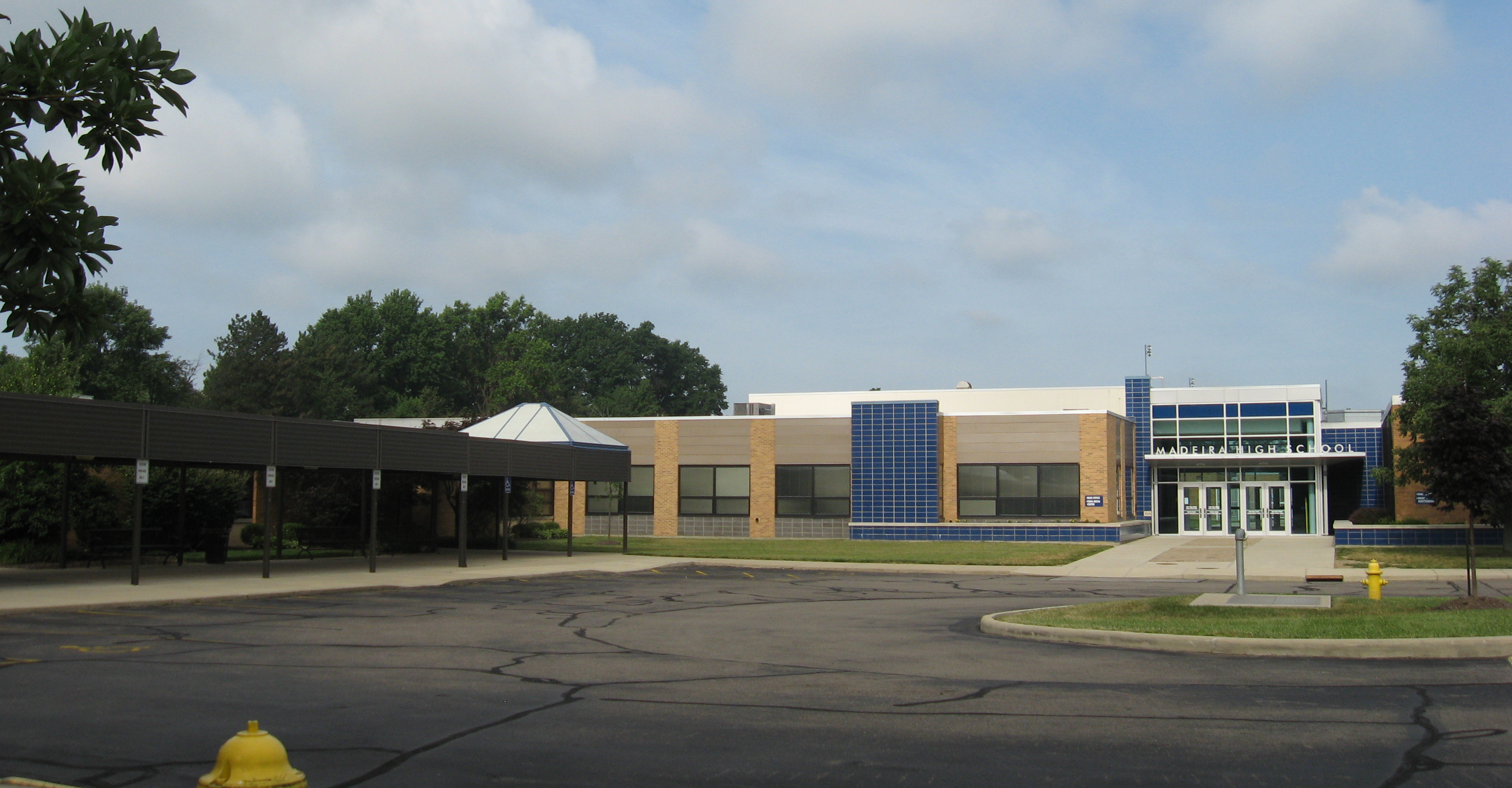 Exterior of a single-story school building with a covered entrance and blue-and-tan facade.