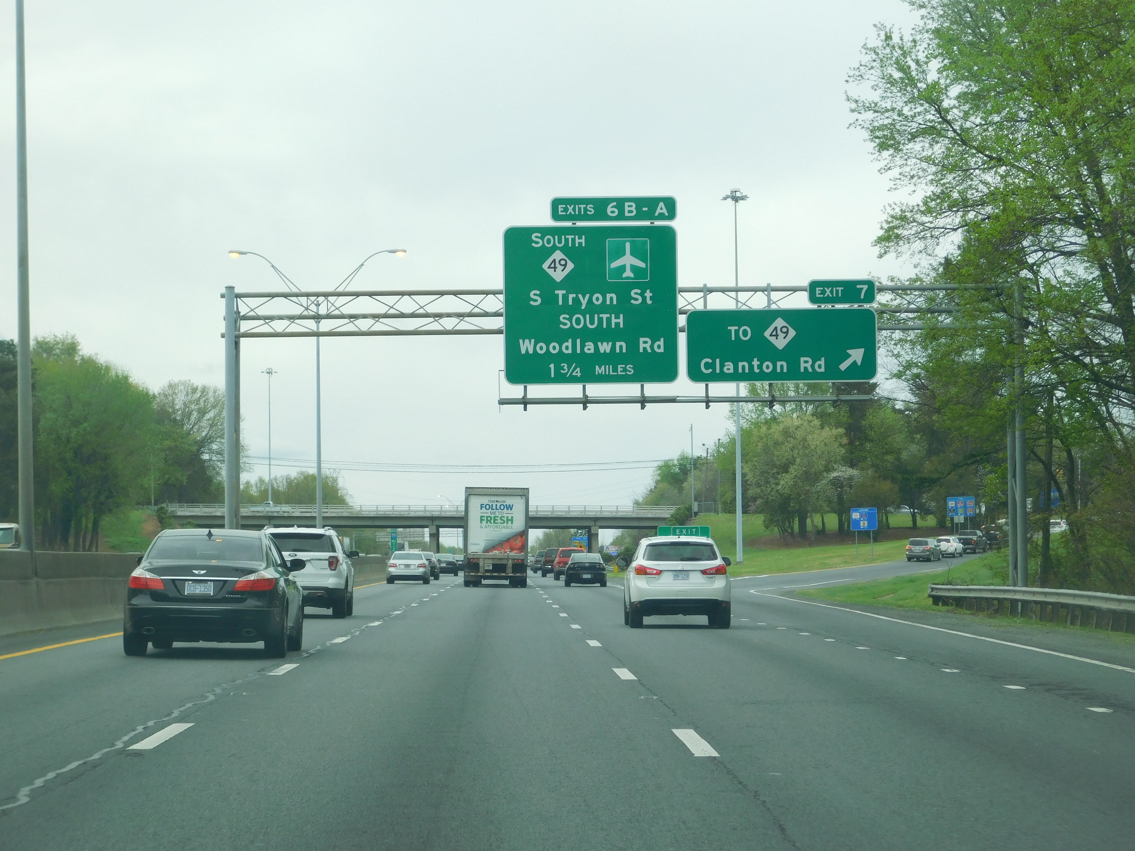 Multi-lane highway with green overhead exit signs on I-77 South in Charlotte.