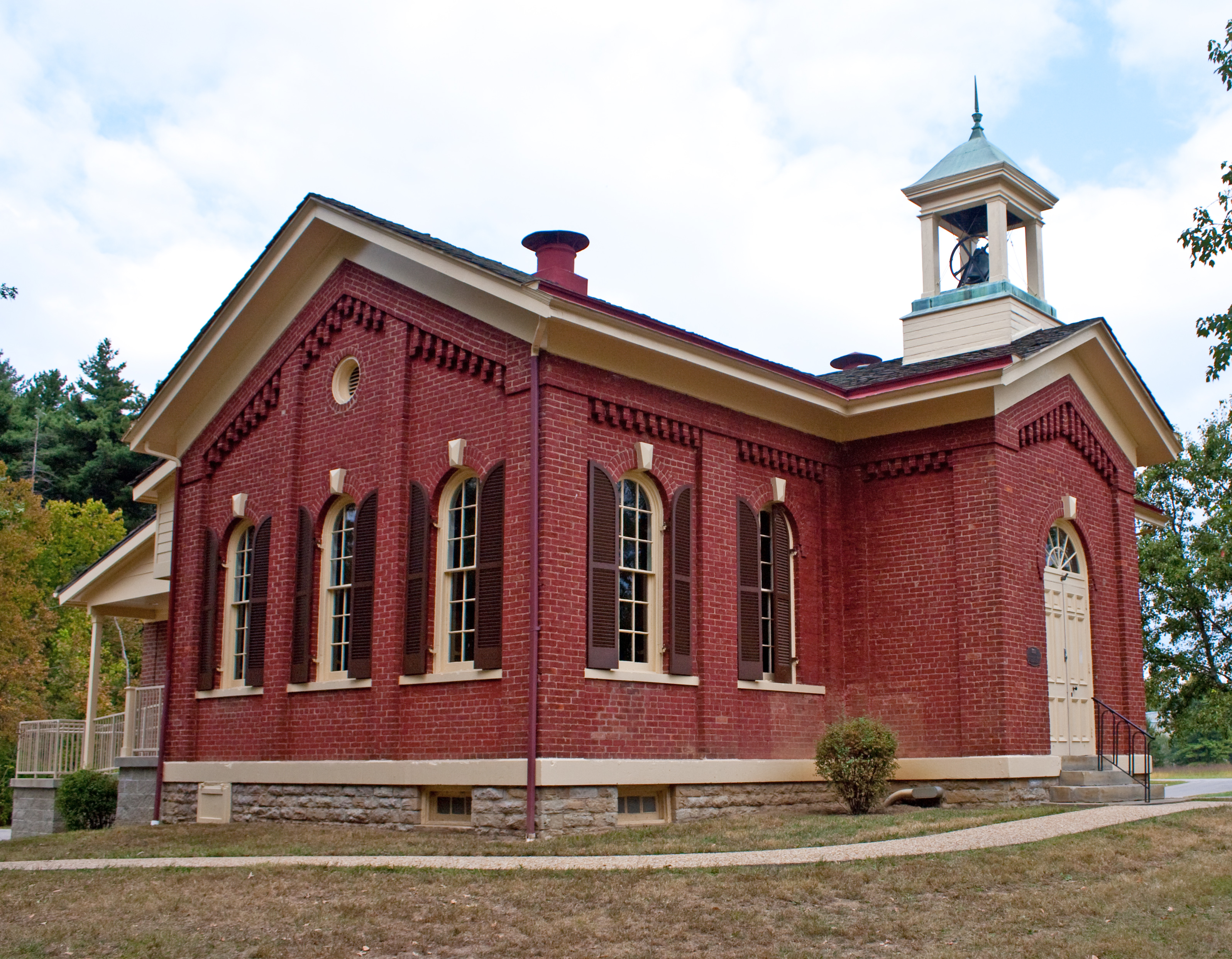 Red brick Victorian school building with arched windows and a copper-topped bell tower.