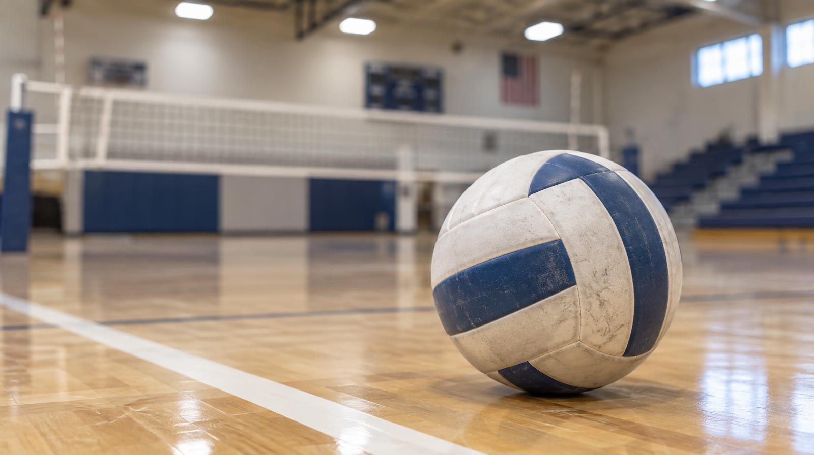 A volleyball resting on a hardwood gymnasium floor beside a painted boundary line, net in background.