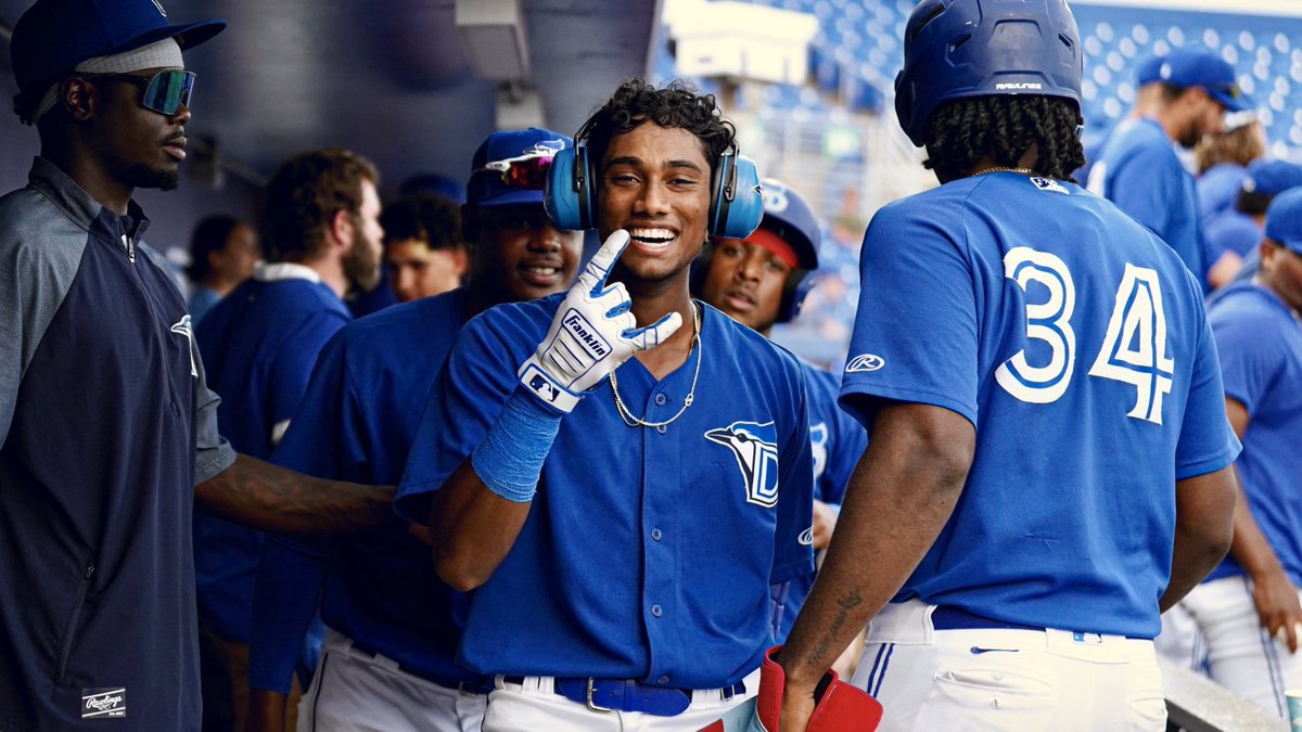 Baseball players in blue uniforms celebrating together in a dugout.