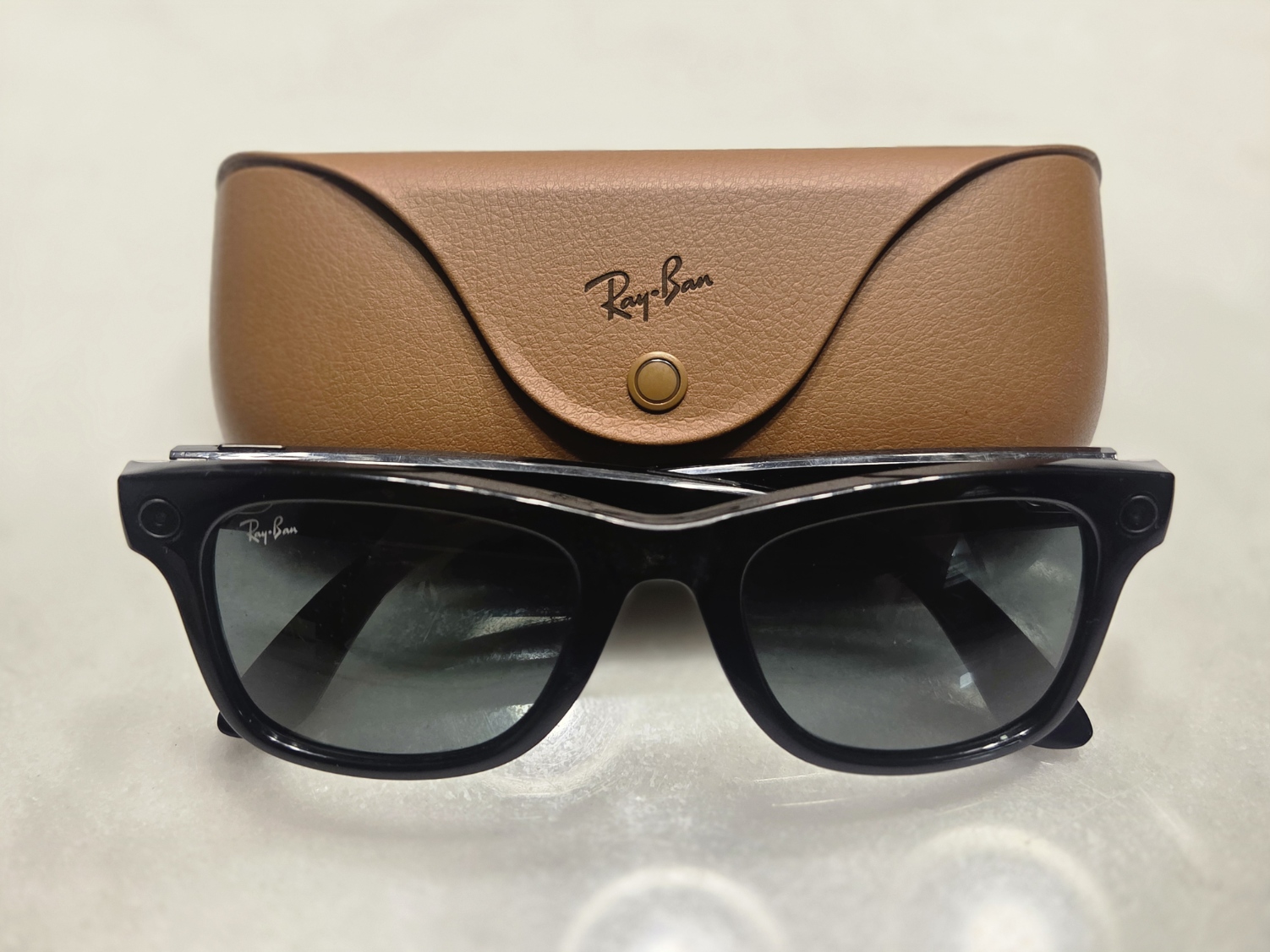 Black Ray-Ban Meta smart glasses resting in front of a brown leather charging case.