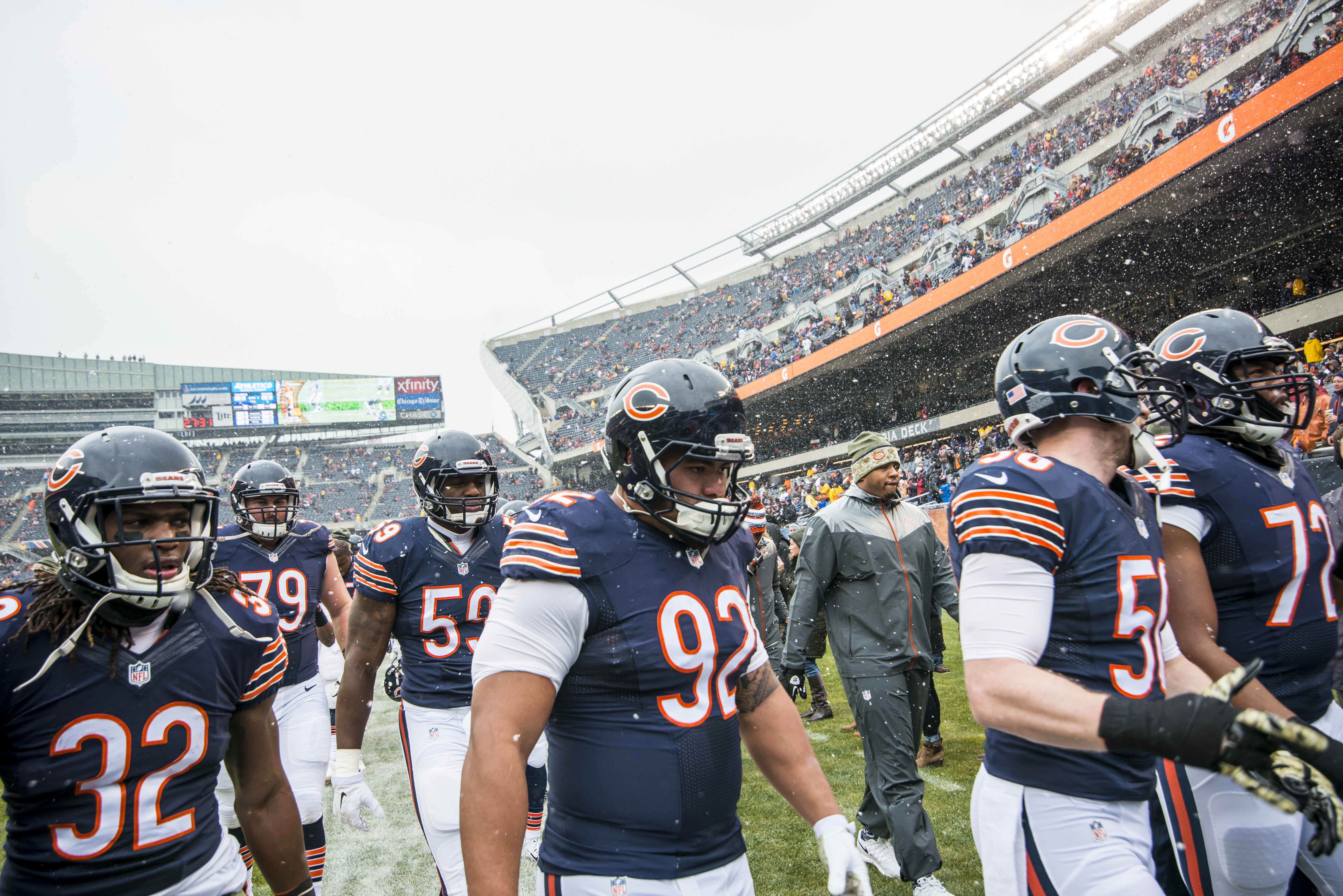 Chicago Bears players in navy uniforms and helmets lined up on a stadium sideline.