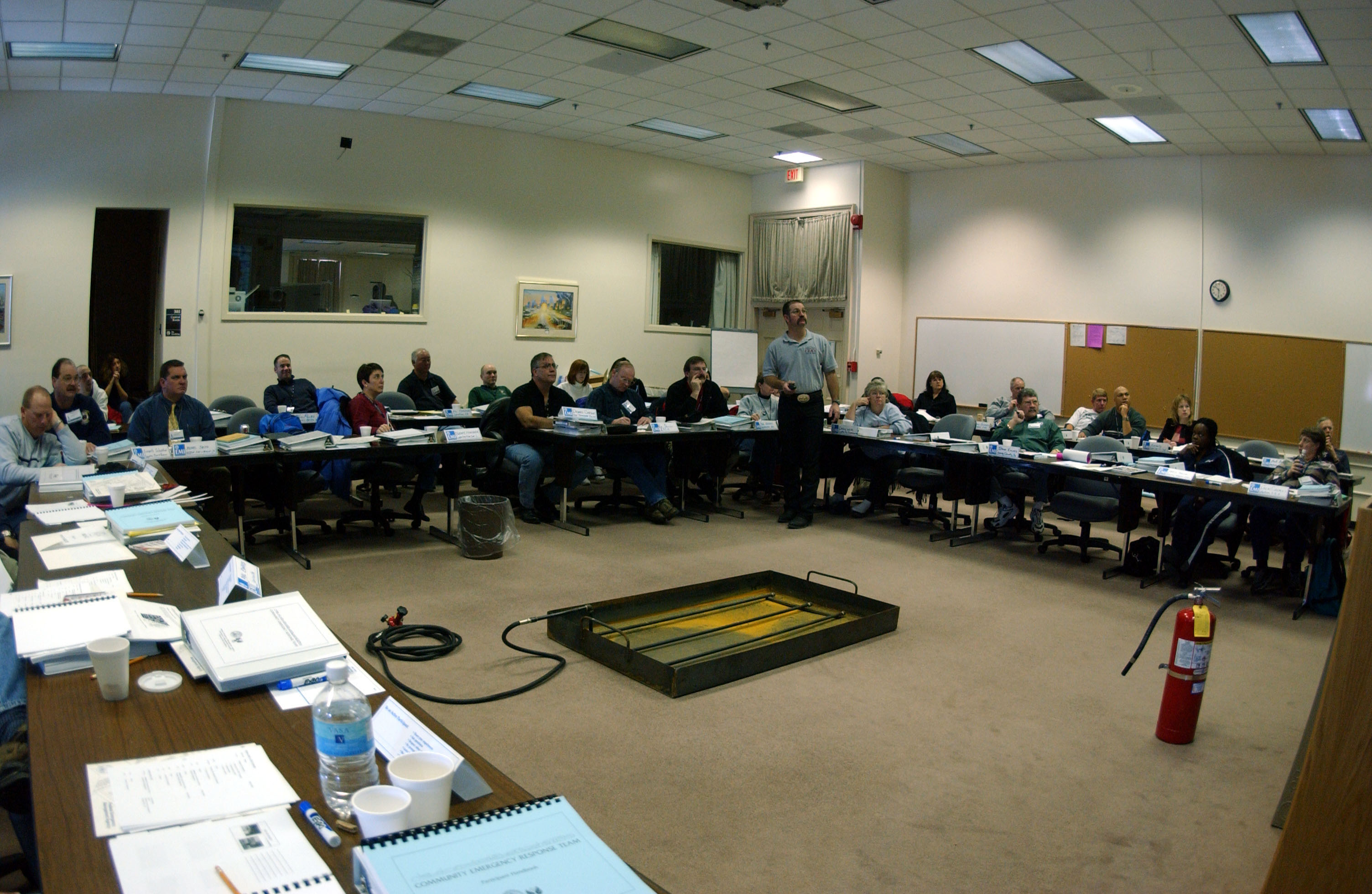 Participants seated at tables in a U-shape during a group emergency response training.