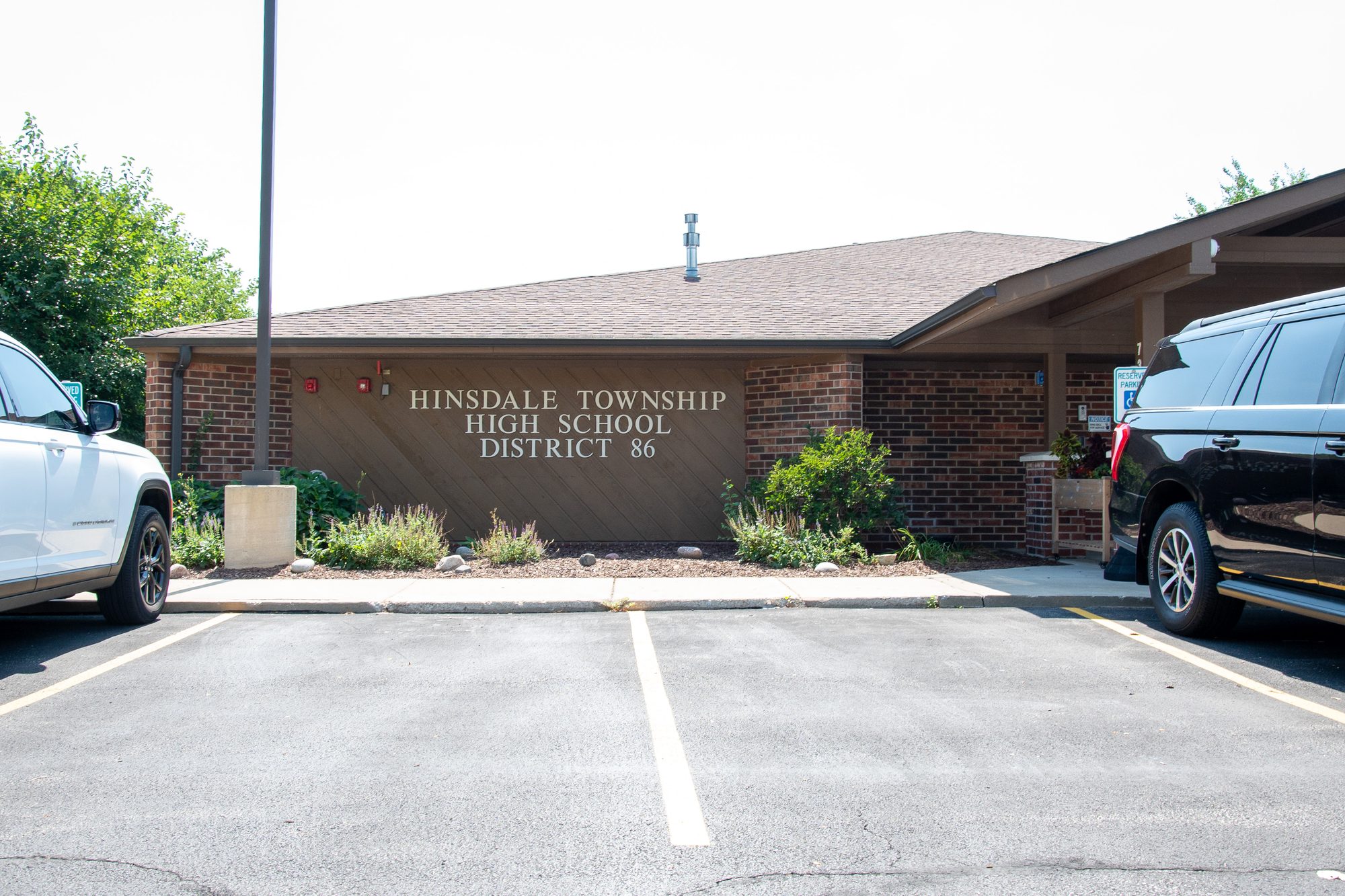 Single-story brick district office building with a sign in a parking lot.