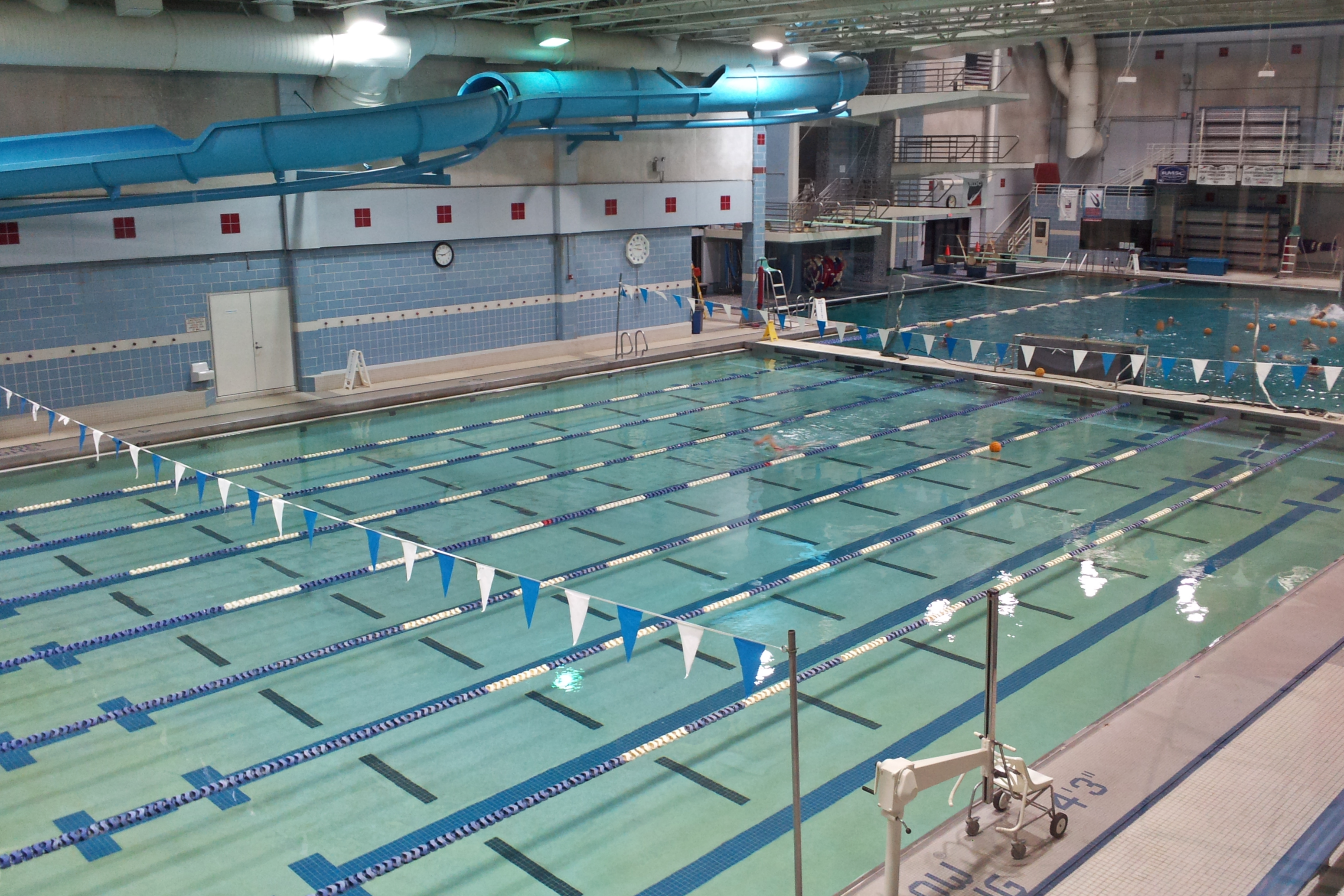 Indoor swimming pool with blue and white lane dividers and overhead lighting.