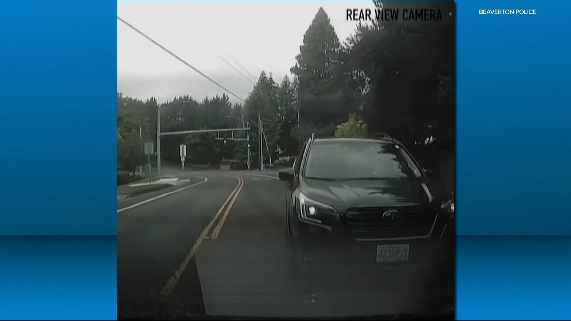 Rear-view dashcam footage showing a dark SUV following closely on a wet street.