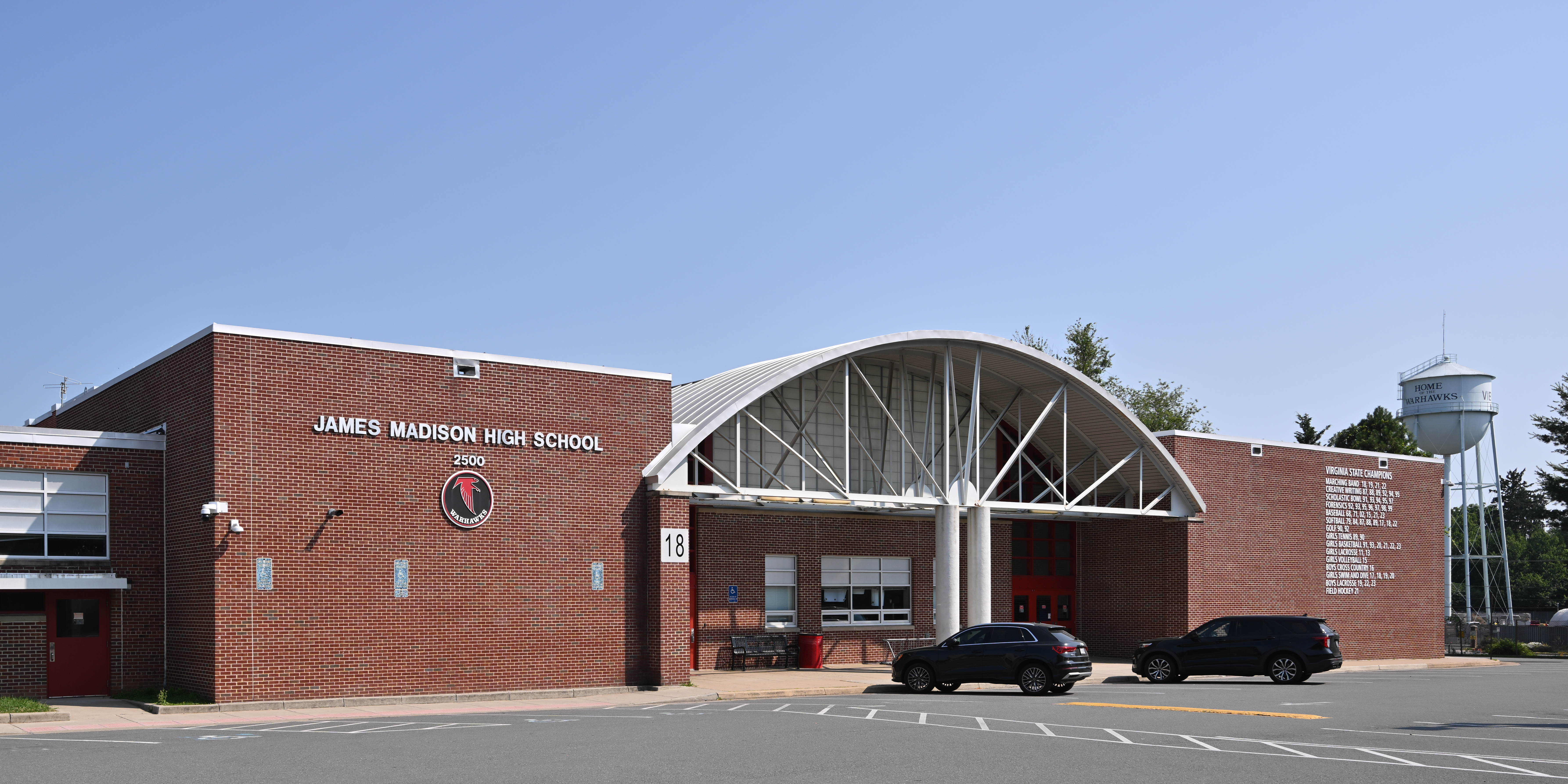 Brick high school entrance with arched white canopy and school name displayed on the facade.