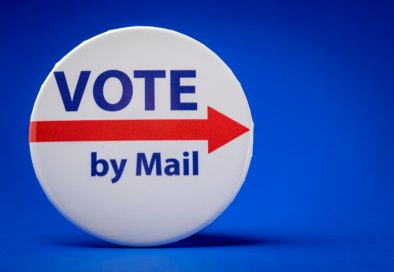 White pinback button with blue and red text reading 'Vote by Mail' on a blue background.