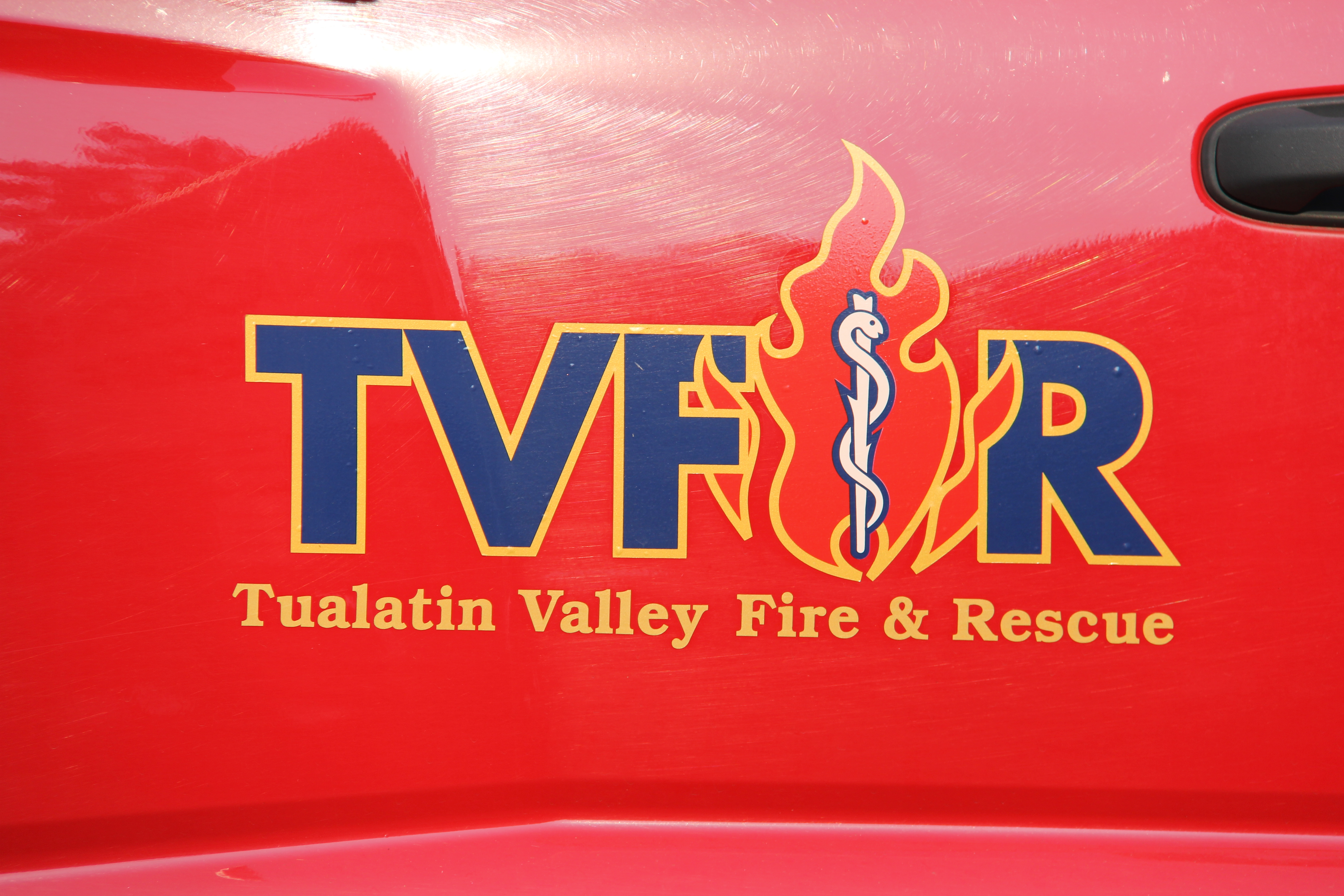 Close-up of the TVF&R logo on the side of a red fire vehicle.