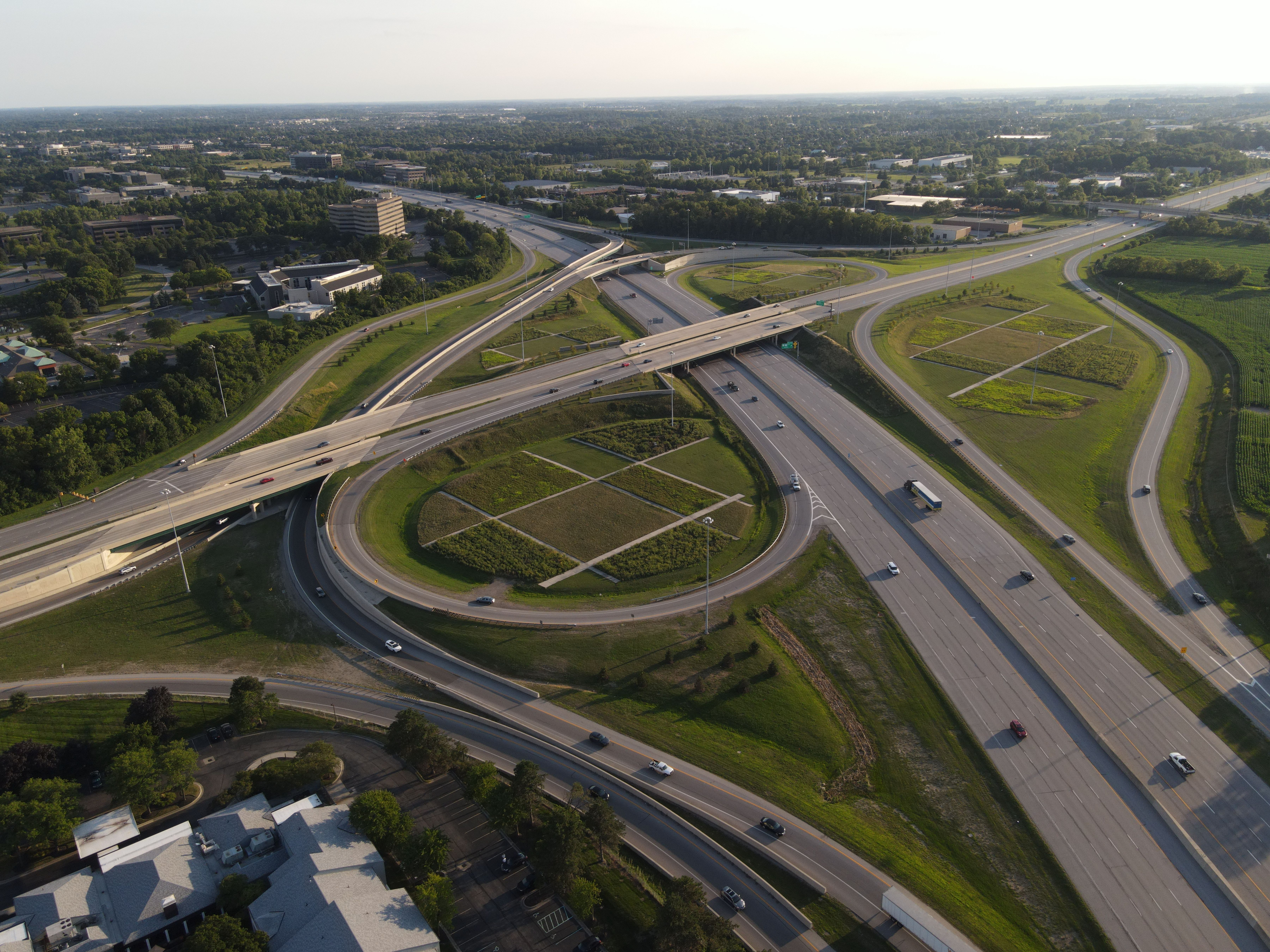 Aerial view of a multi-lane highway interchange with looping ramps and green medians.