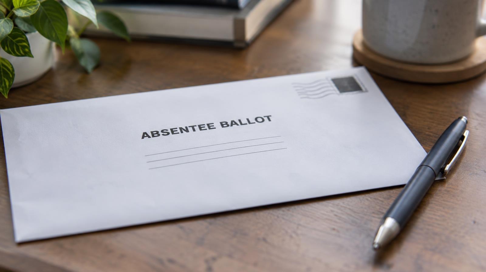 A sealed white envelope and a pen resting on a flat surface.