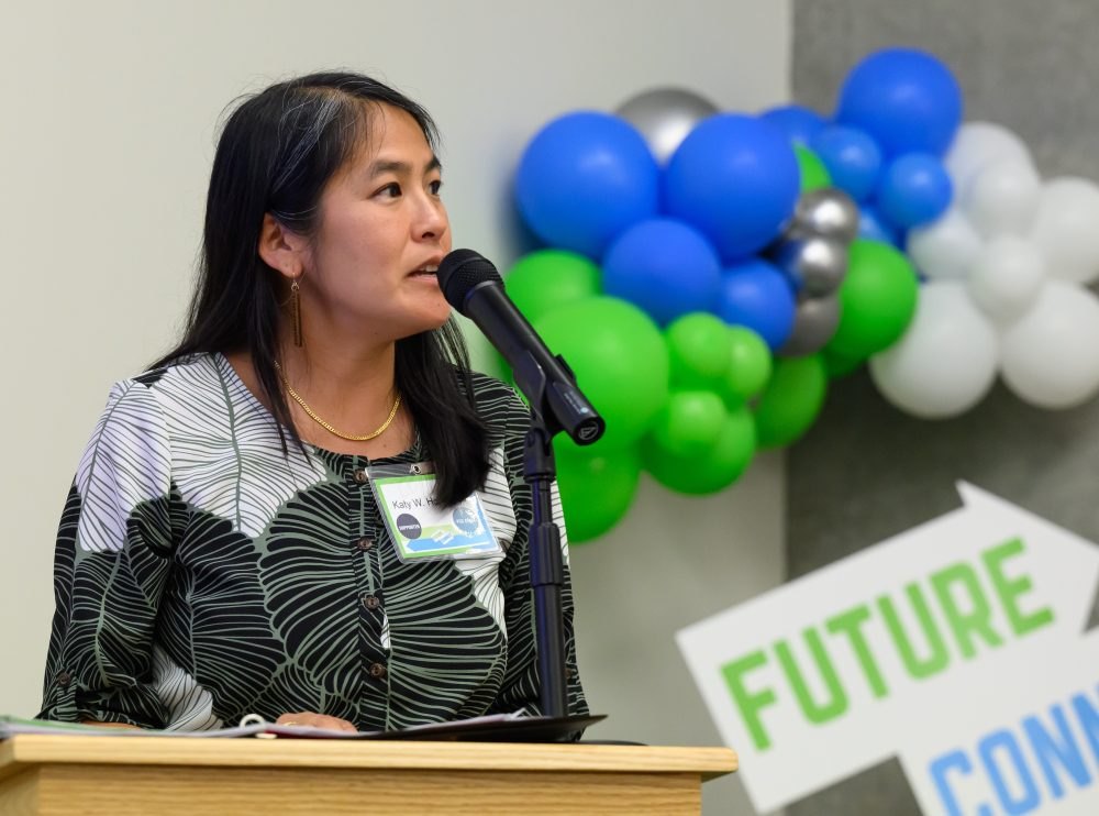 A woman speaks at a podium with balloons and a Future Connect sign behind her.