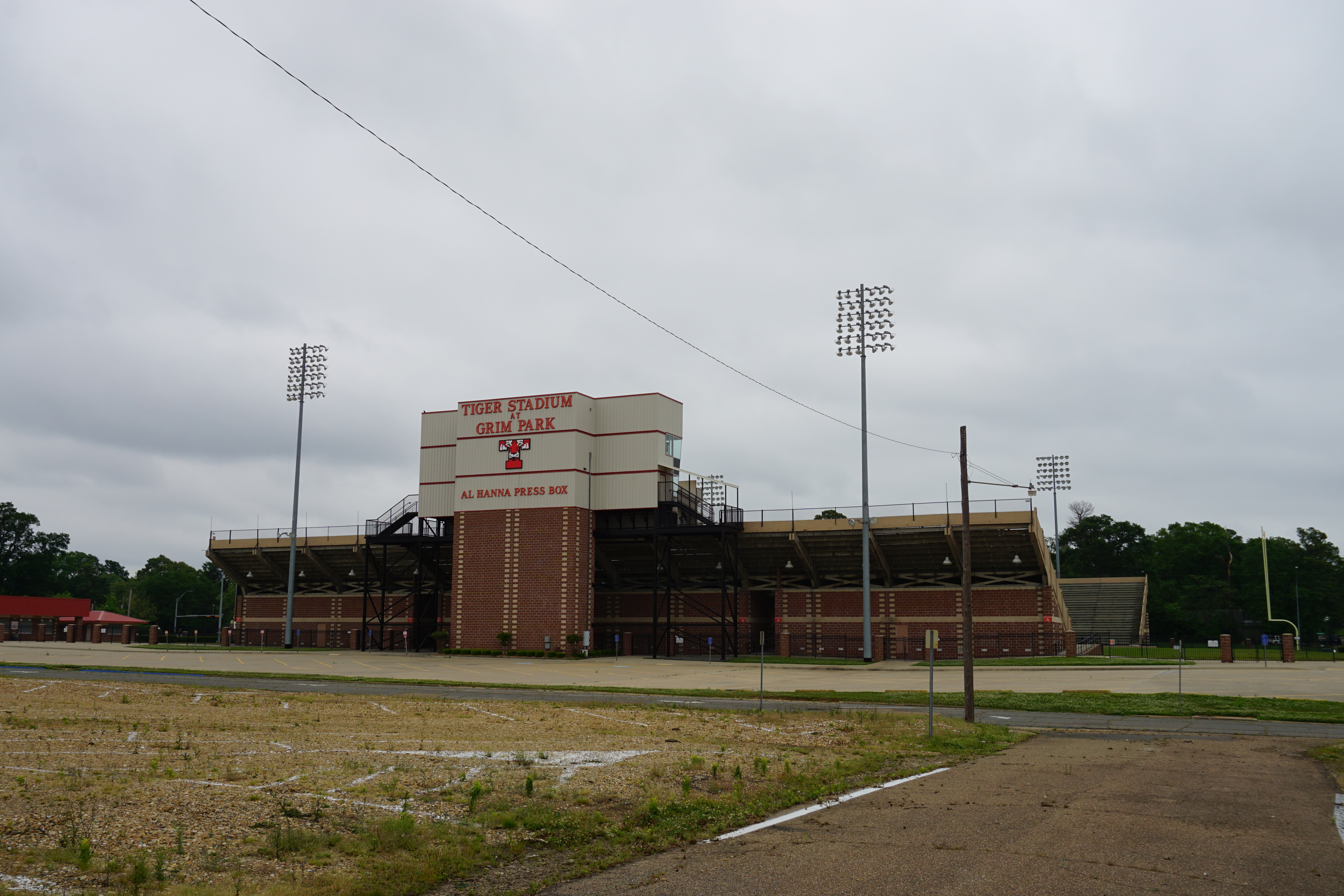 Brick exterior of a high school football stadium with press box tower and stadium lights.