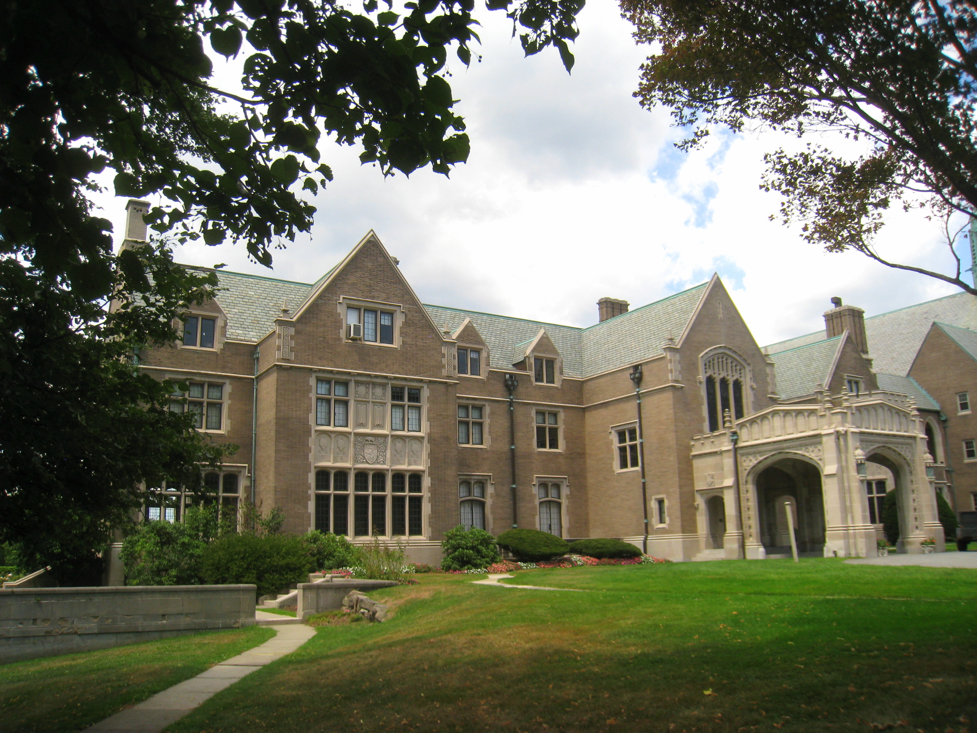 Brick Gothic-style school building with an ornate arched entrance and green lawn.